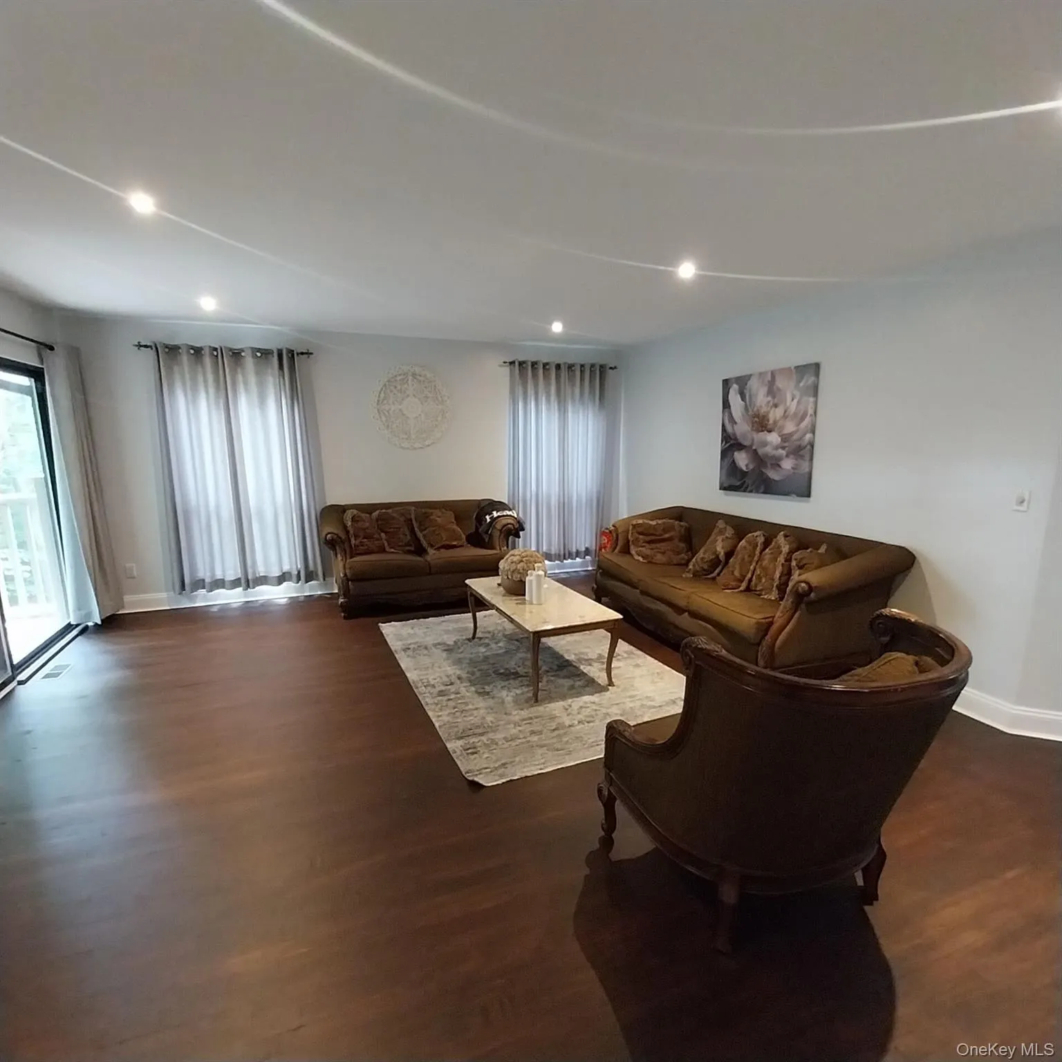 Spacious interior featuring dark wood-finish flooring, recessed lighting, and white baseboards Spacious interior featuring dark wood-finish flooring, recessed lighting, and white baseboards