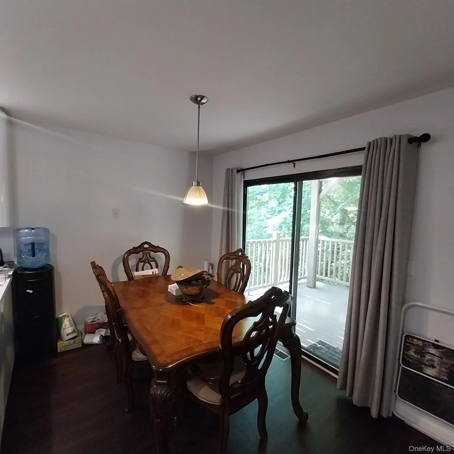 Sliding glass door leading to an exterior deck, dark wood-finish flooring, and a pendant light fixture Sliding glass door leading to an exterior deck, dark wood-finish flooring, and a pendant light fixture