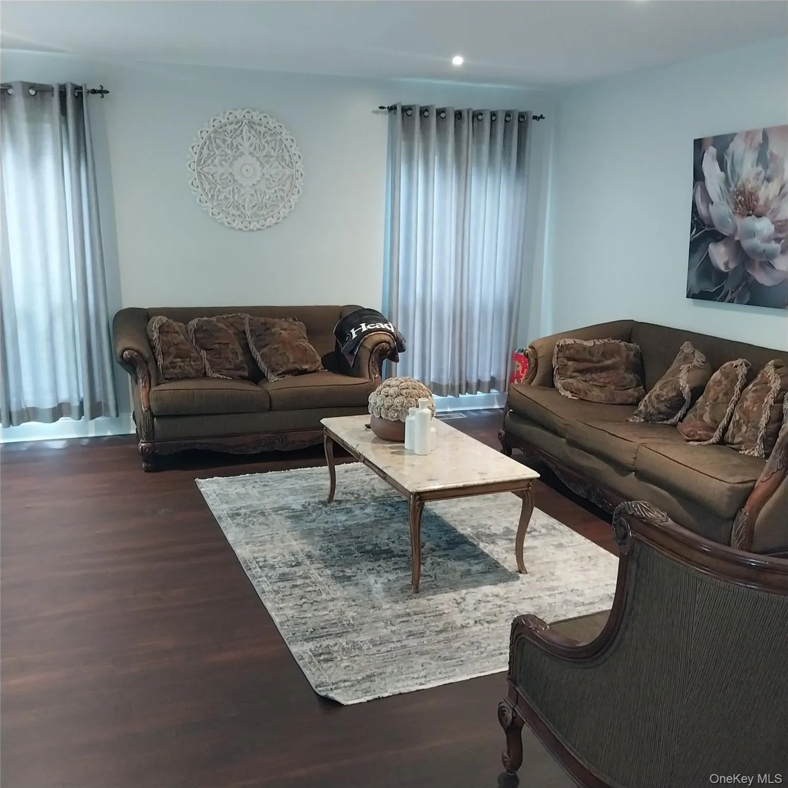 Spacious living area featuring dark wood-finish flooring, recessed lighting, and ample natural light from multiple windows Spacious living area featuring dark wood-finish flooring, recessed lighting, and ample natural light from multiple windows