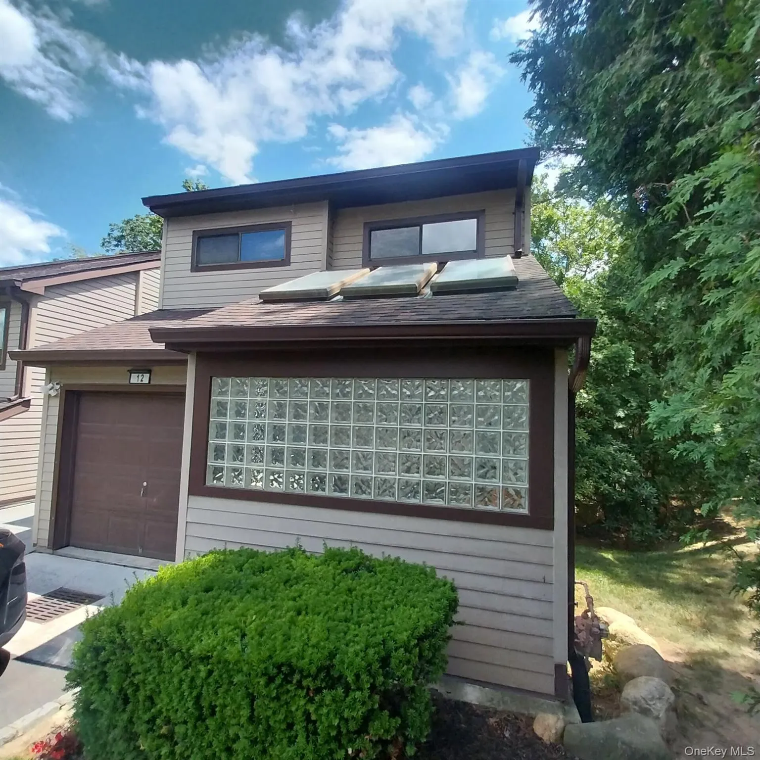 Contemporary exterior featuring siding, a dark brown garage door, and a glass block window Contemporary exterior featuring siding, a dark brown garage door, and a glass block window