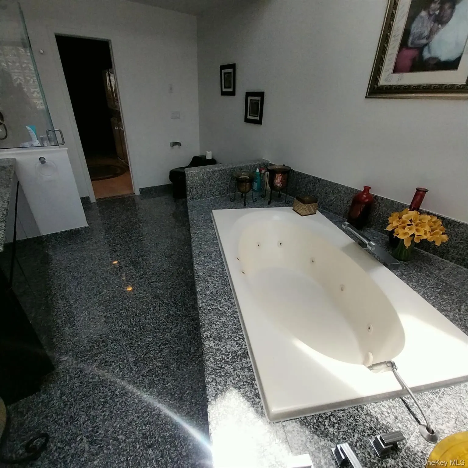 Built-in jetted tub surrounded by a polished stone countertop, featuring an integrated faucet Built-in jetted tub surrounded by a polished stone countertop, featuring an integrated faucet