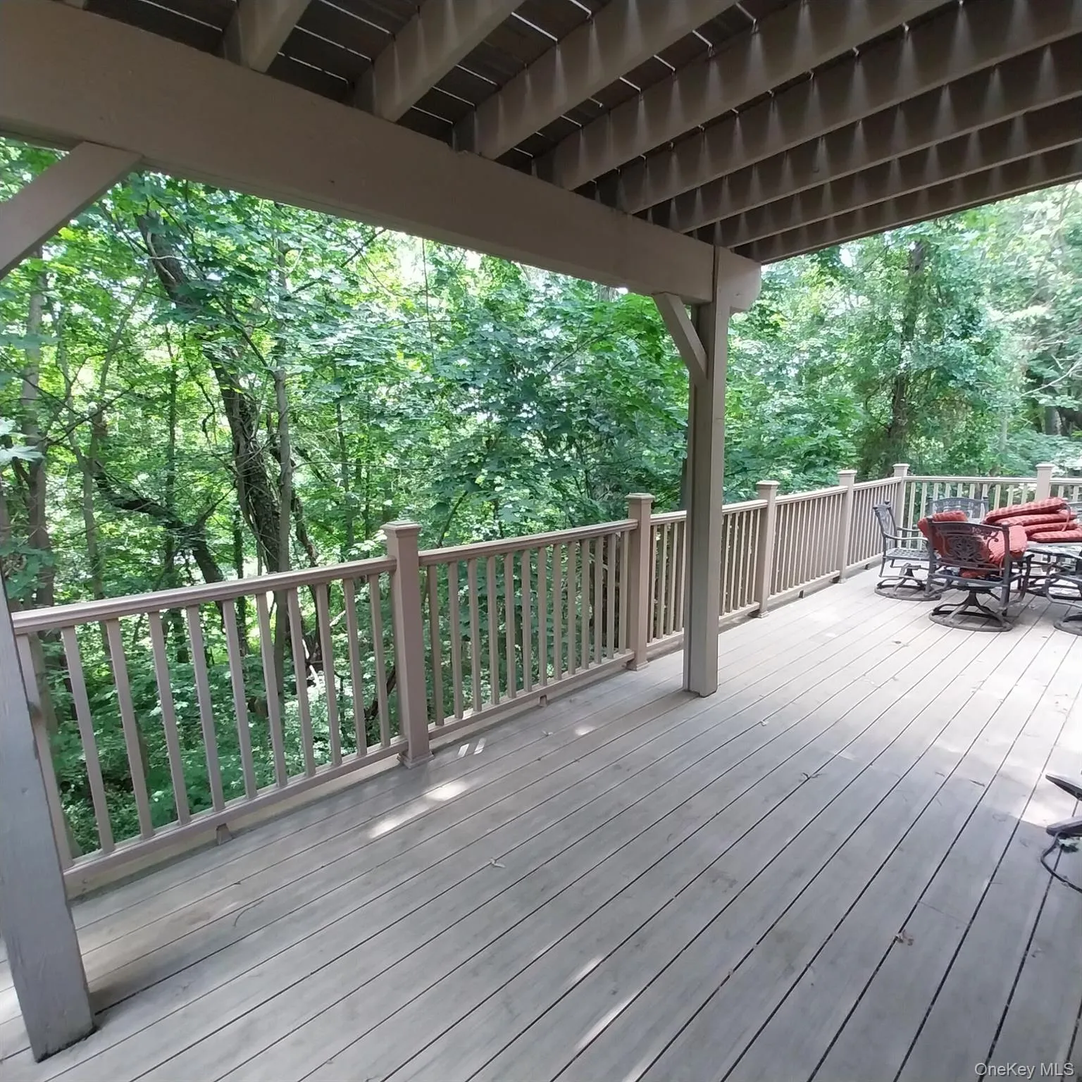 Expansive outdoor deck featuring wood-finish flooring, a full-length perimeter railing, and a covered ceiling structure Expansive outdoor deck featuring wood-finish flooring, a full-length perimeter railing, and a covered ceiling structure