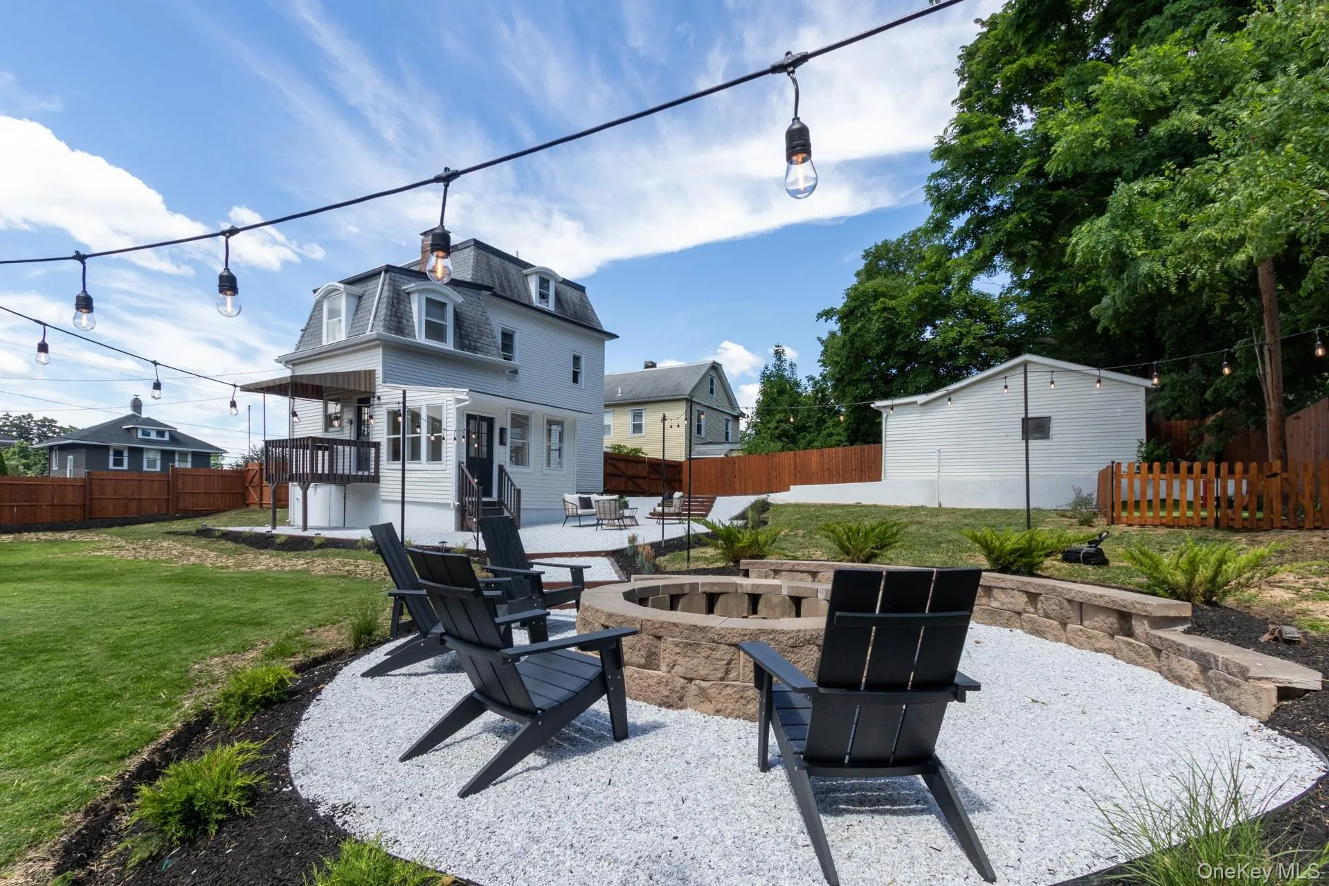 Backyard fire pit area with gravel ground cover, stone block retaining wall, and string lighting Backyard fire pit area with gravel ground cover, stone block retaining wall, and string lighting