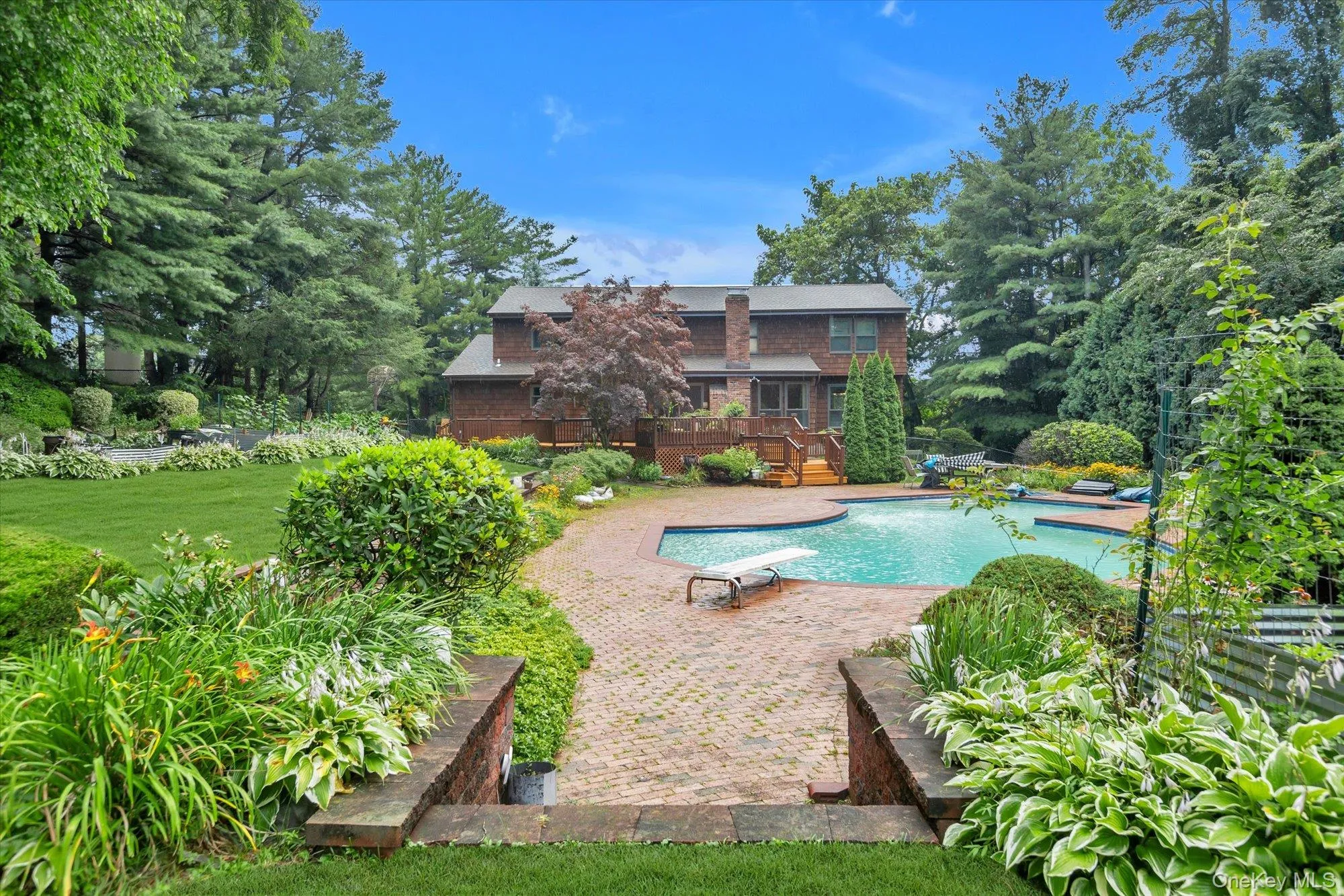 Spacious backyard featuring a brick paver patio, in-ground swimming pool, and tiered landscaping Spacious backyard featuring a brick paver patio, in-ground swimming pool, and tiered landscaping