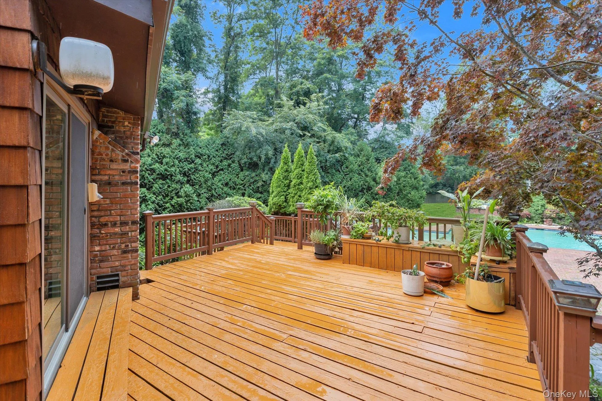 Expansive outdoor deck featuring wood-finish decking, a built-in planter, and wood railings Expansive outdoor deck featuring wood-finish decking, a built-in planter, and wood railings