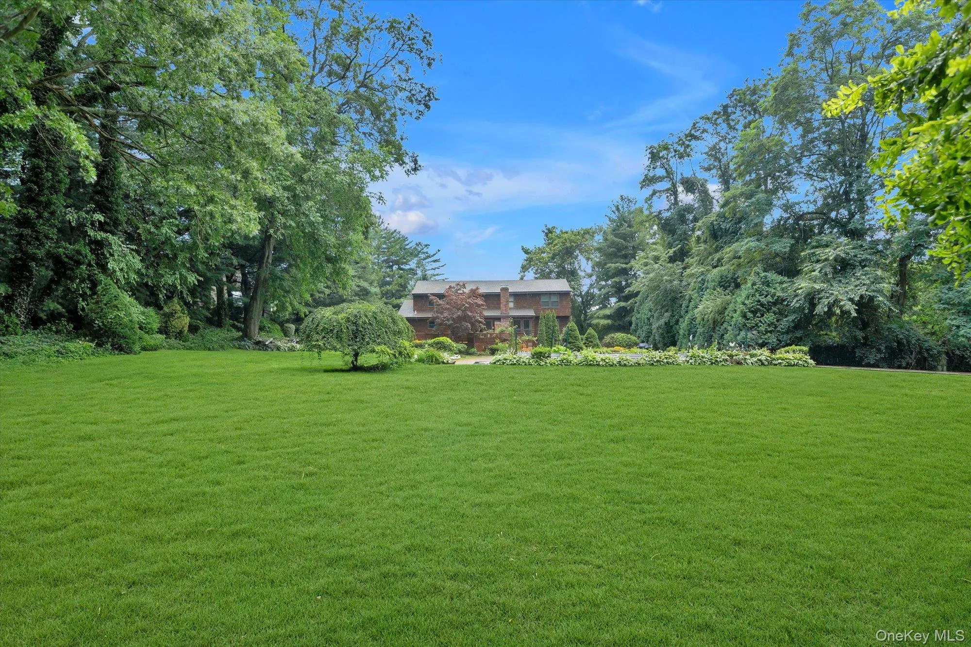 Expansive green lawn with mature trees framing a traditional colonial style home. Expansive green lawn with mature trees framing a traditional colonial style home.