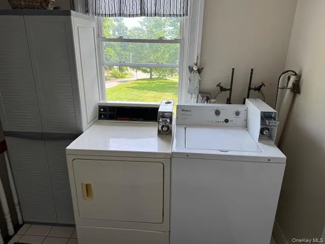 Washroom featuring washer and clothes dryer and light tile patterned flooring Washroom featuring washer and clothes dryer and light tile patterned flooring