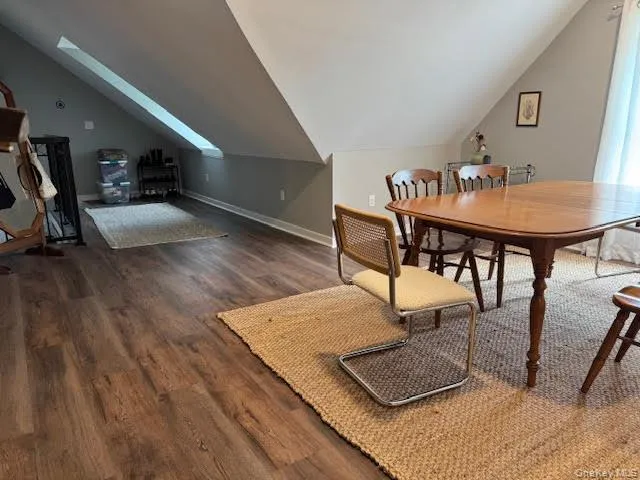 Dining room featuring vaulted ceiling, wood finished floors, and a skylight Dining room featuring vaulted ceiling, wood finished floors, and a skylight