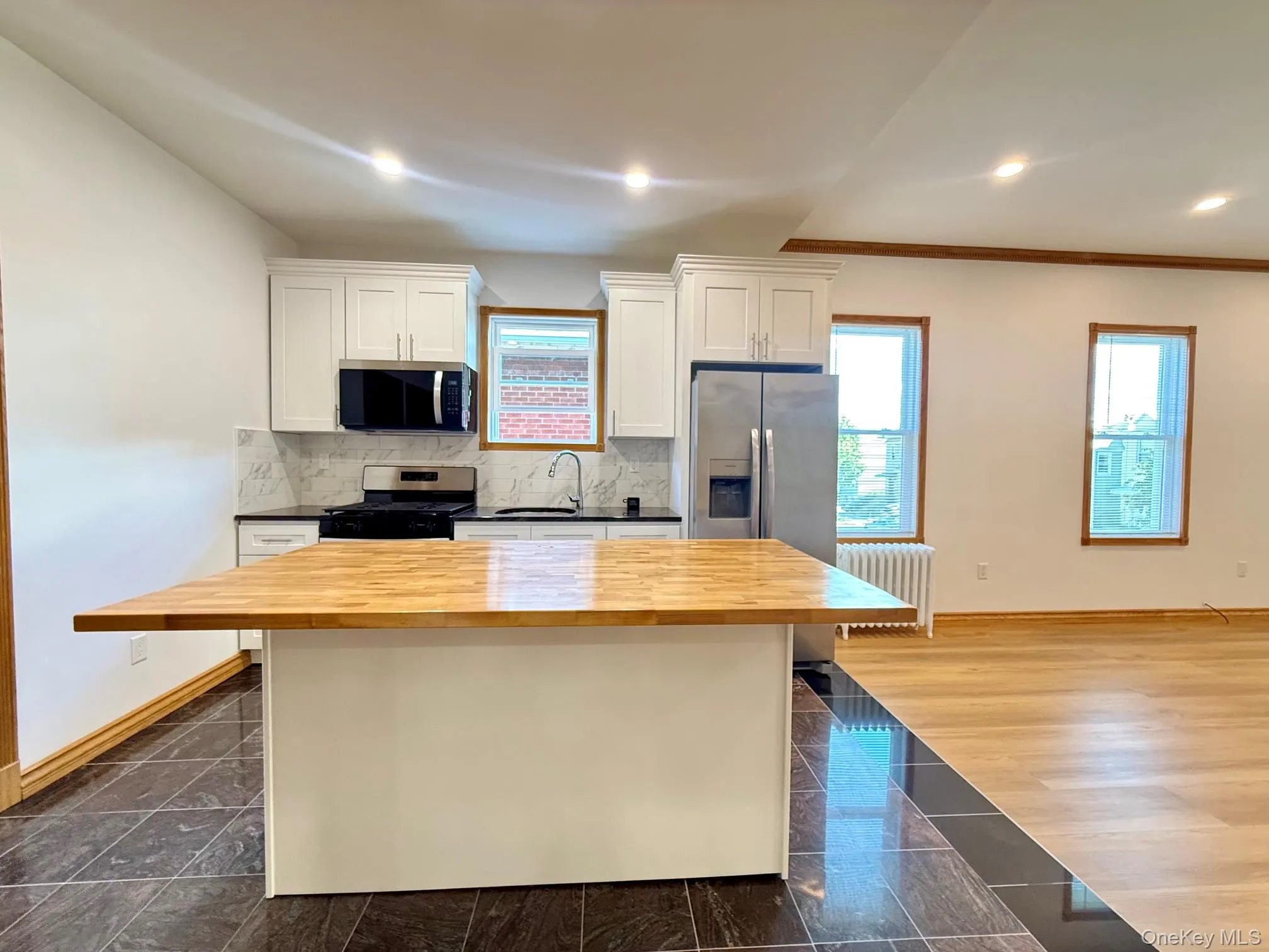 Kitchen featuring a center island with a wood-finish countertop, white cabinetry, and stainless steel appliances Kitchen featuring a center island with a wood-finish countertop, white cabinetry, and stainless steel appliances