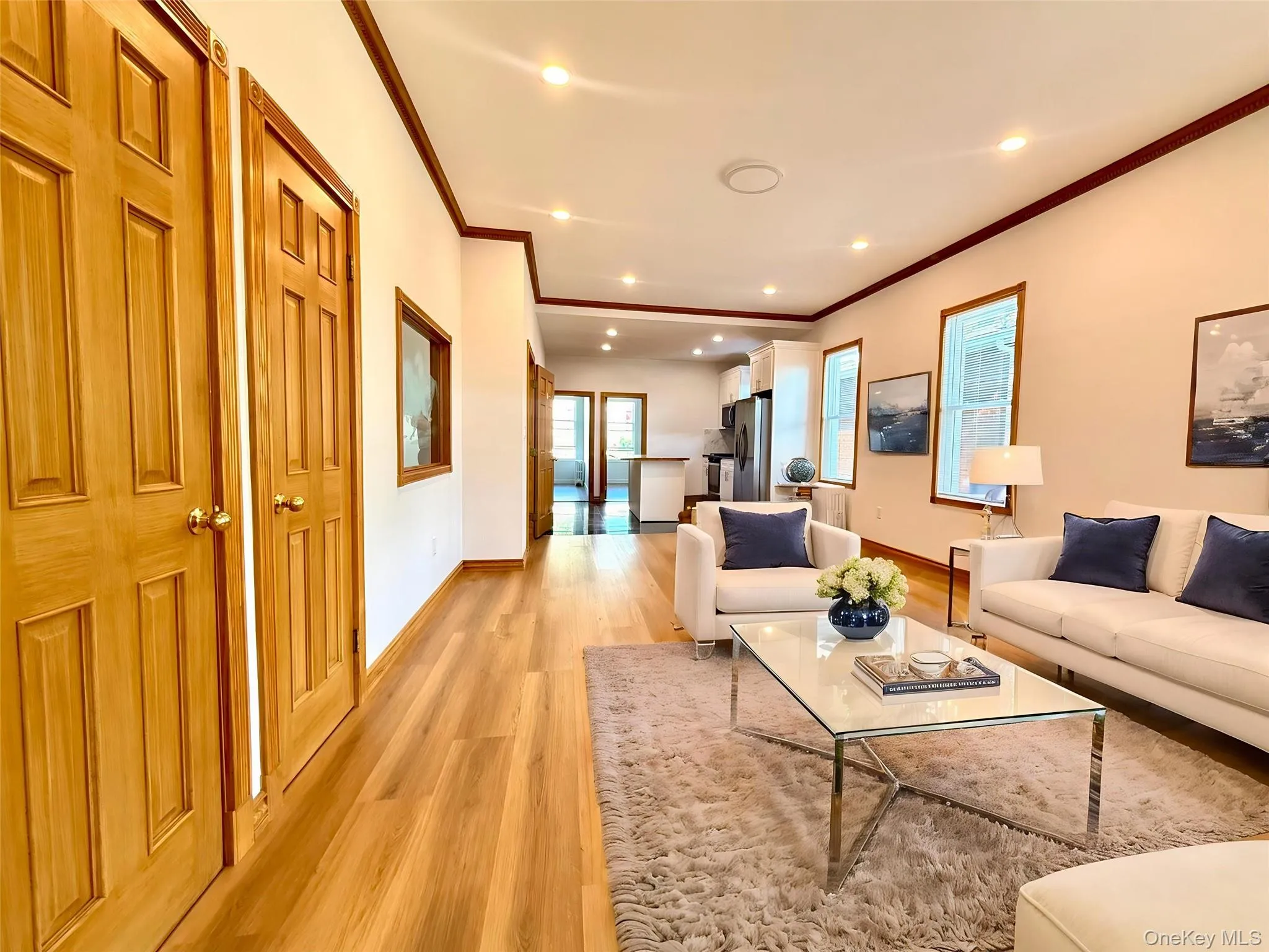 Bright living space featuring wood-finish flooring, recessed lighting, and crown molding Bright living space featuring wood-finish flooring, recessed lighting, and crown molding