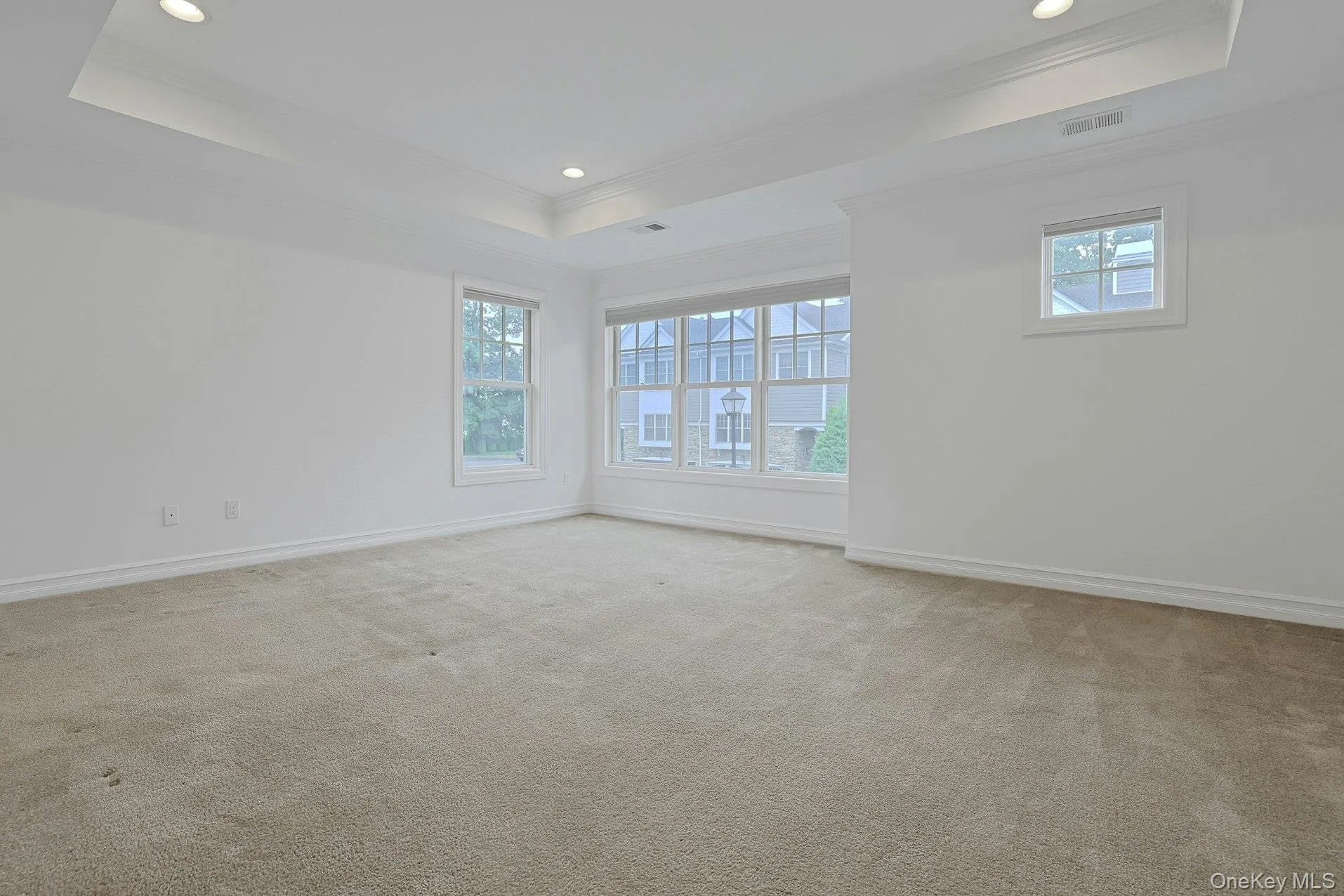 The spacious primary suite offers a peaceful retreat with a tray ceiling, abundant natural light, and ample room for a king-sized bedroom set and sitting area. The spacious primary suite offers a peaceful retreat with a tray ceiling, abundant natural light, and ample room for a king-sized bedroom set and sitting area.