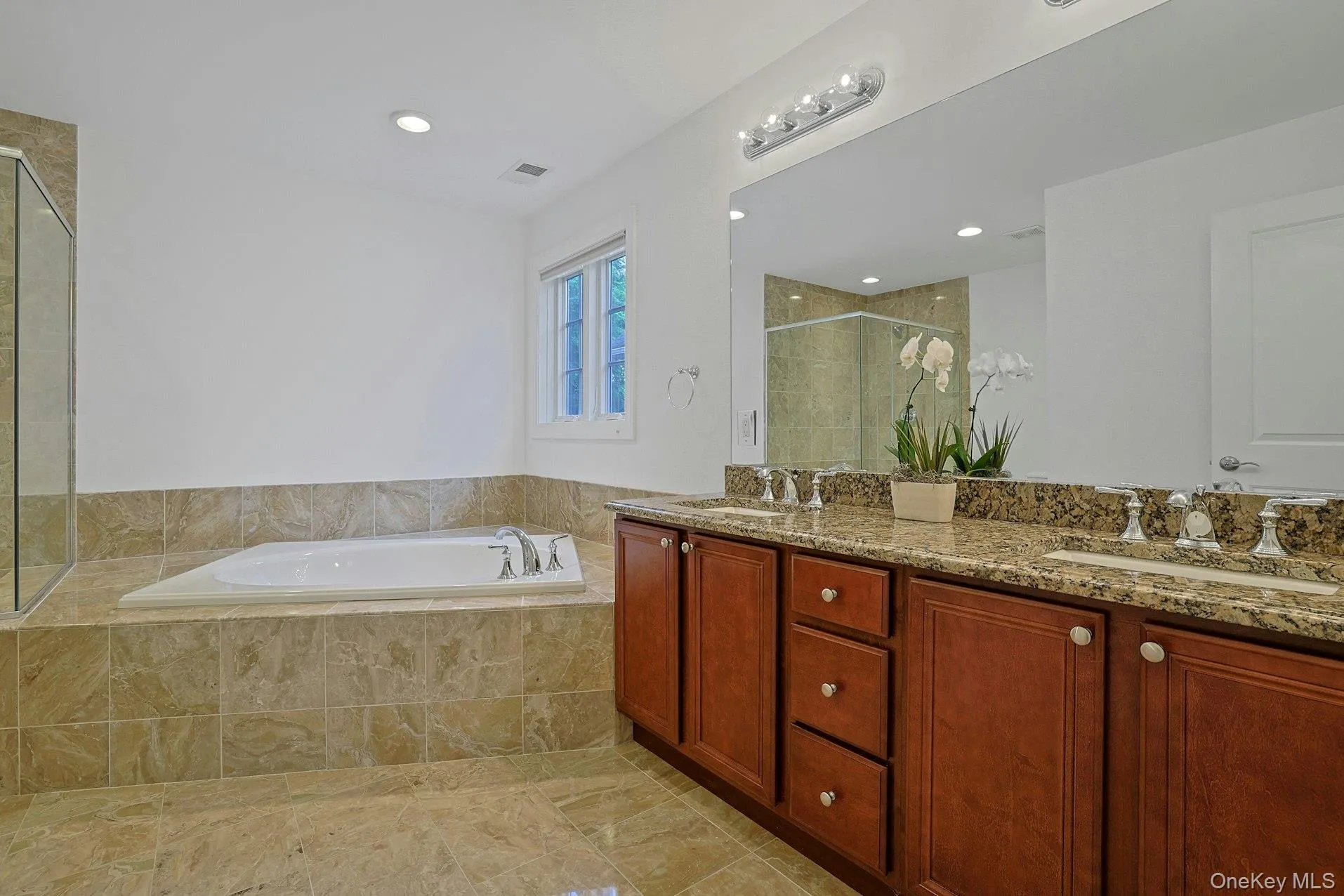 Designed for relaxation, the spa-like primary bath features a double granite vanity, abundant cabinetry, and elegant stone tile finishes throughout. Designed for relaxation, the spa-like primary bath features a double granite vanity, abundant cabinetry, and elegant stone tile finishes throughout.