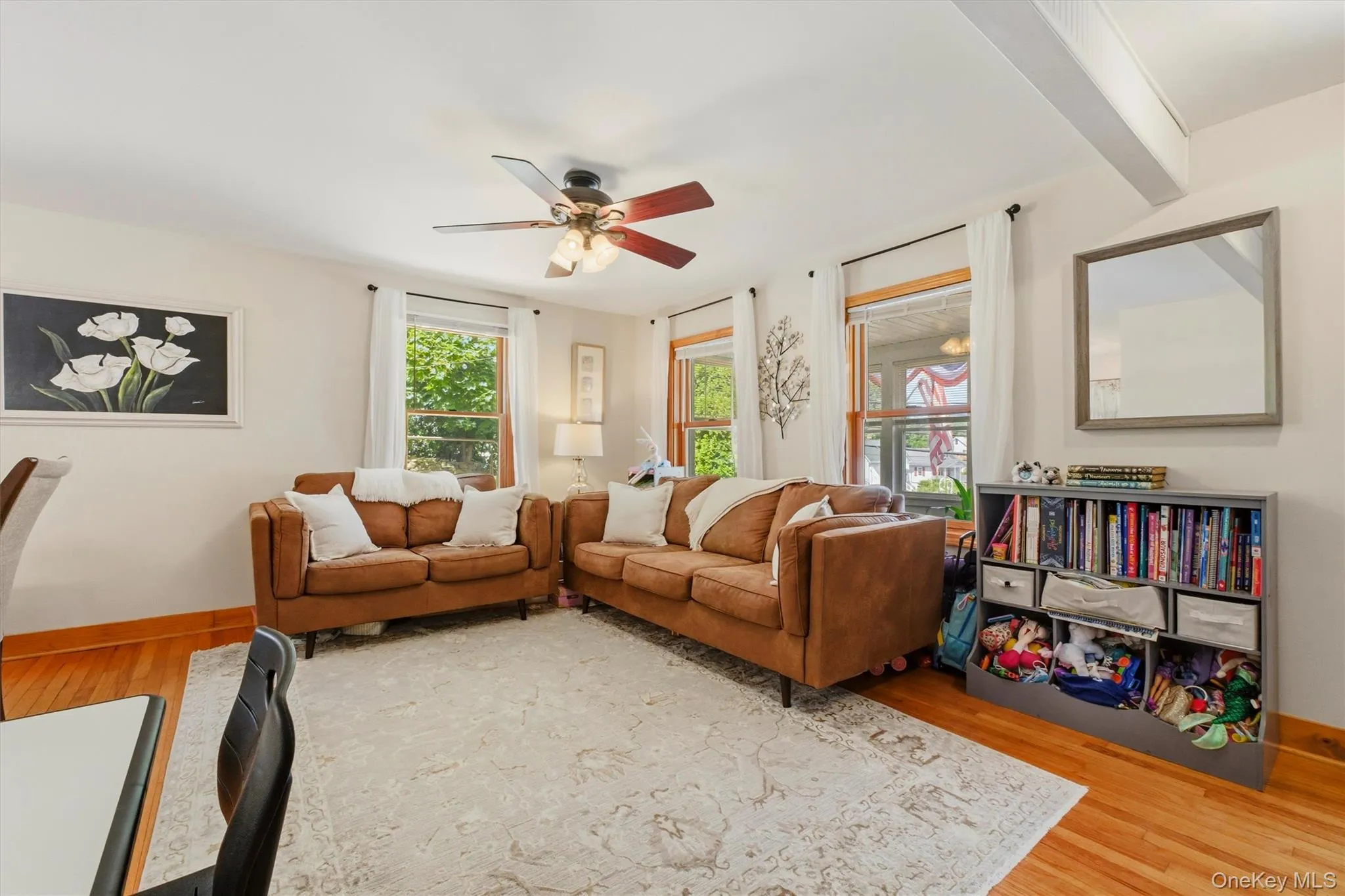 The sun filled living room is accented with hardwood flooring and large windows. The sun filled living room is accented with hardwood flooring and large windows.