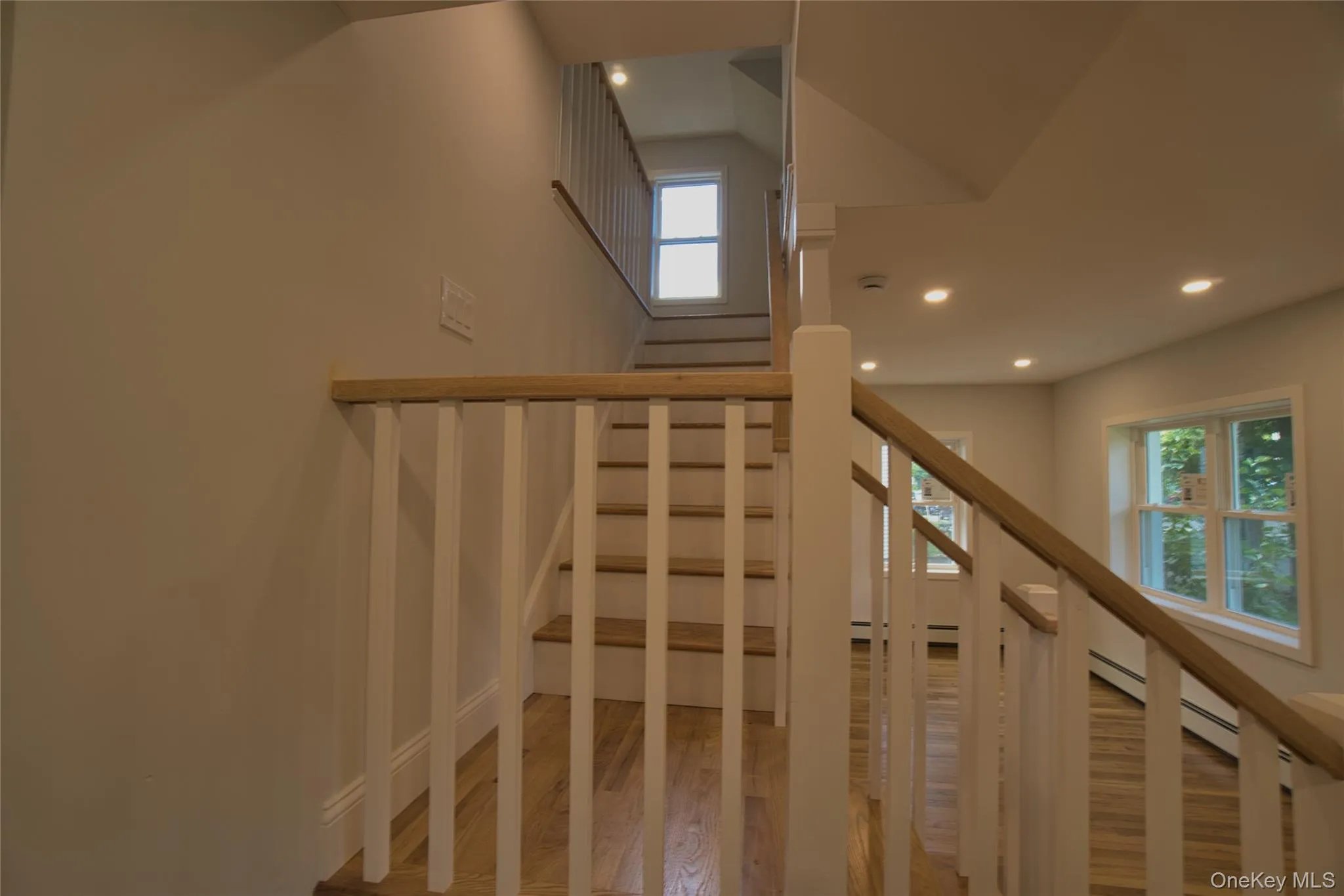 Staircase featuring wood-finish treads and handrails with white balusters Staircase featuring wood-finish treads and handrails with white balusters
