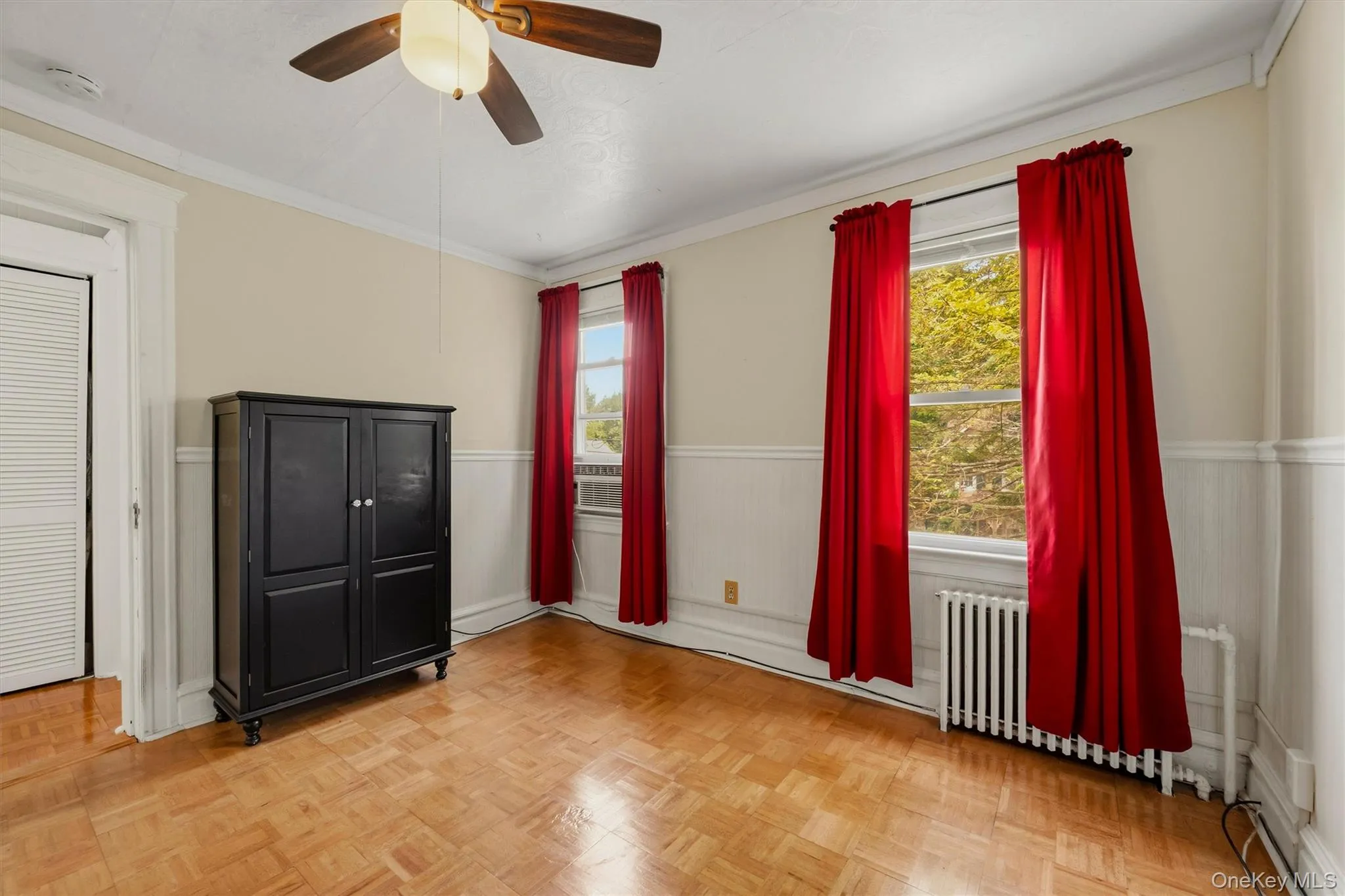 Parquet wood flooring, a ceiling fan with light fixture, and wainscoting details Parquet wood flooring, a ceiling fan with light fixture, and wainscoting details