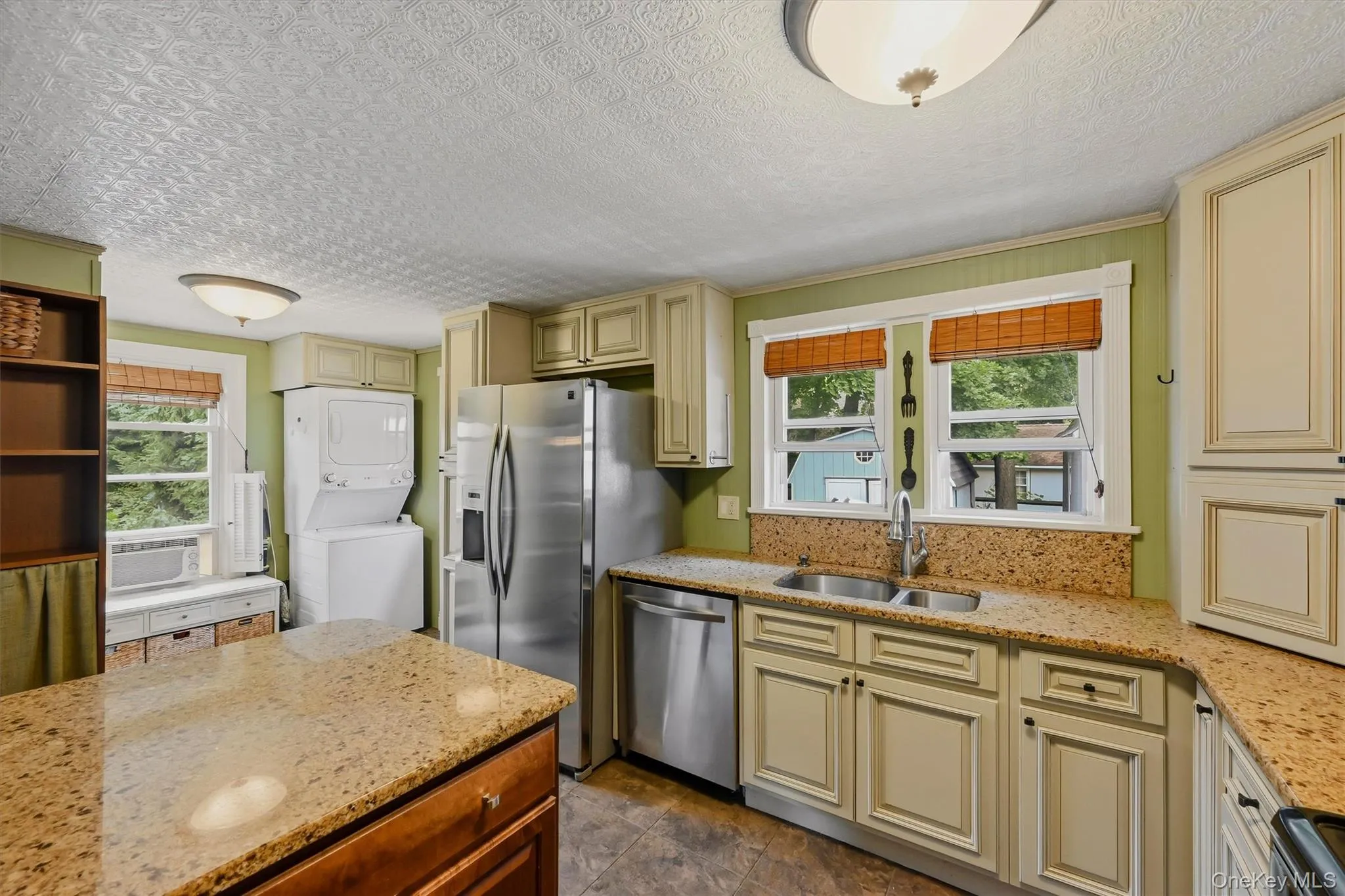 Kitchen with cream-colored cabinetry, granite-style countertops, and stainless steel appliances Kitchen with cream-colored cabinetry, granite-style countertops, and stainless steel appliances