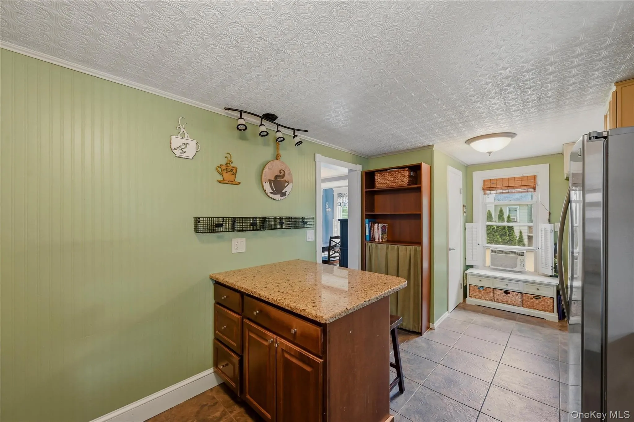 Kitchen island featuring a granite-style countertop, wood cabinetry, and track lighting Kitchen island featuring a granite-style countertop, wood cabinetry, and track lighting