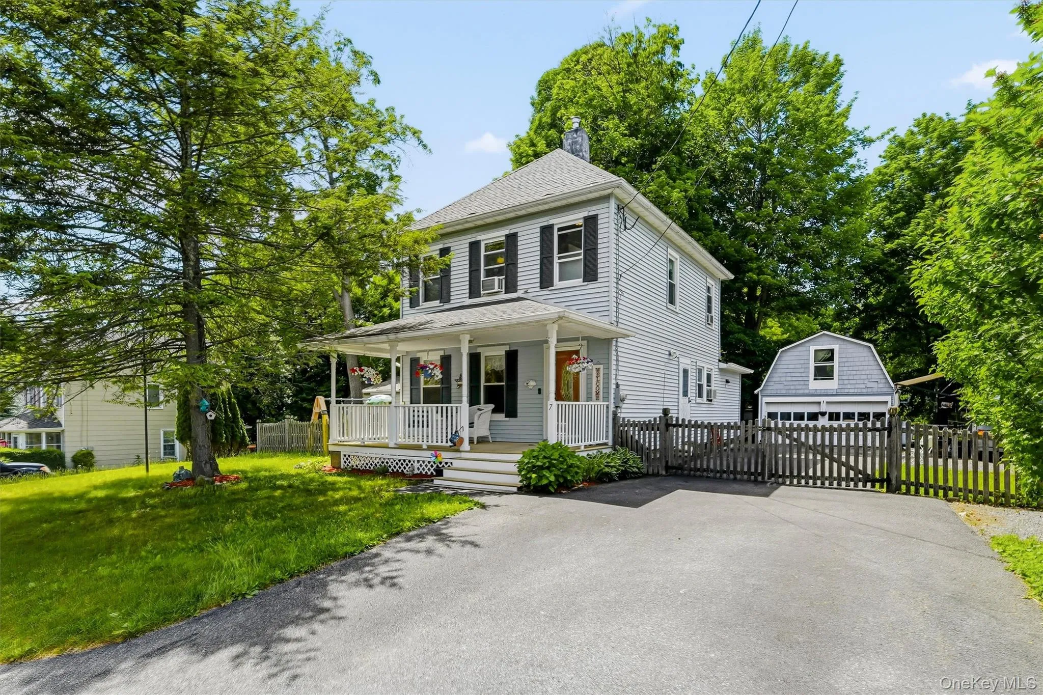 Traditional two-story residence featuring light gray siding and a covered front porch with white railings Traditional two-story residence featuring light gray siding and a covered front porch with white railings