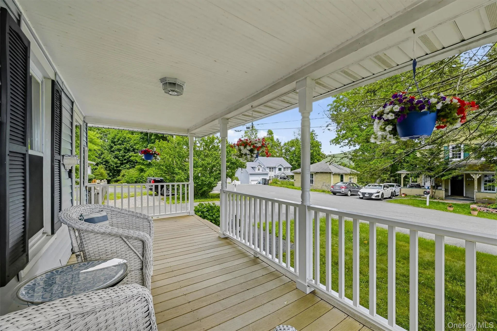 Inviting covered porch with wood-finish flooring, white railing, and a beadboard ceiling Inviting covered porch with wood-finish flooring, white railing, and a beadboard ceiling