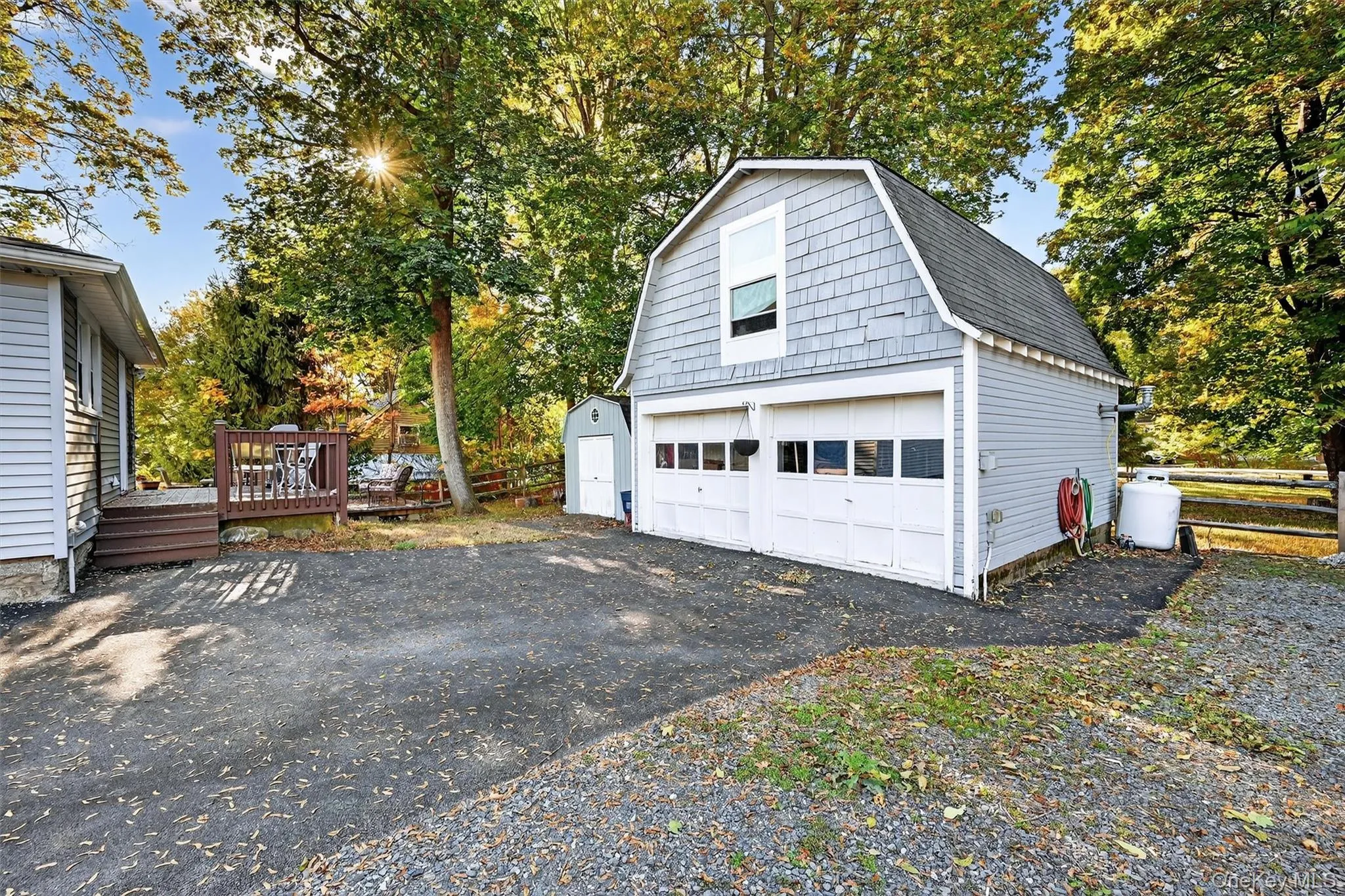 Detached two-car garage with gambrel roof, shingle siding, and upper-level window Detached two-car garage with gambrel roof, shingle siding, and upper-level window