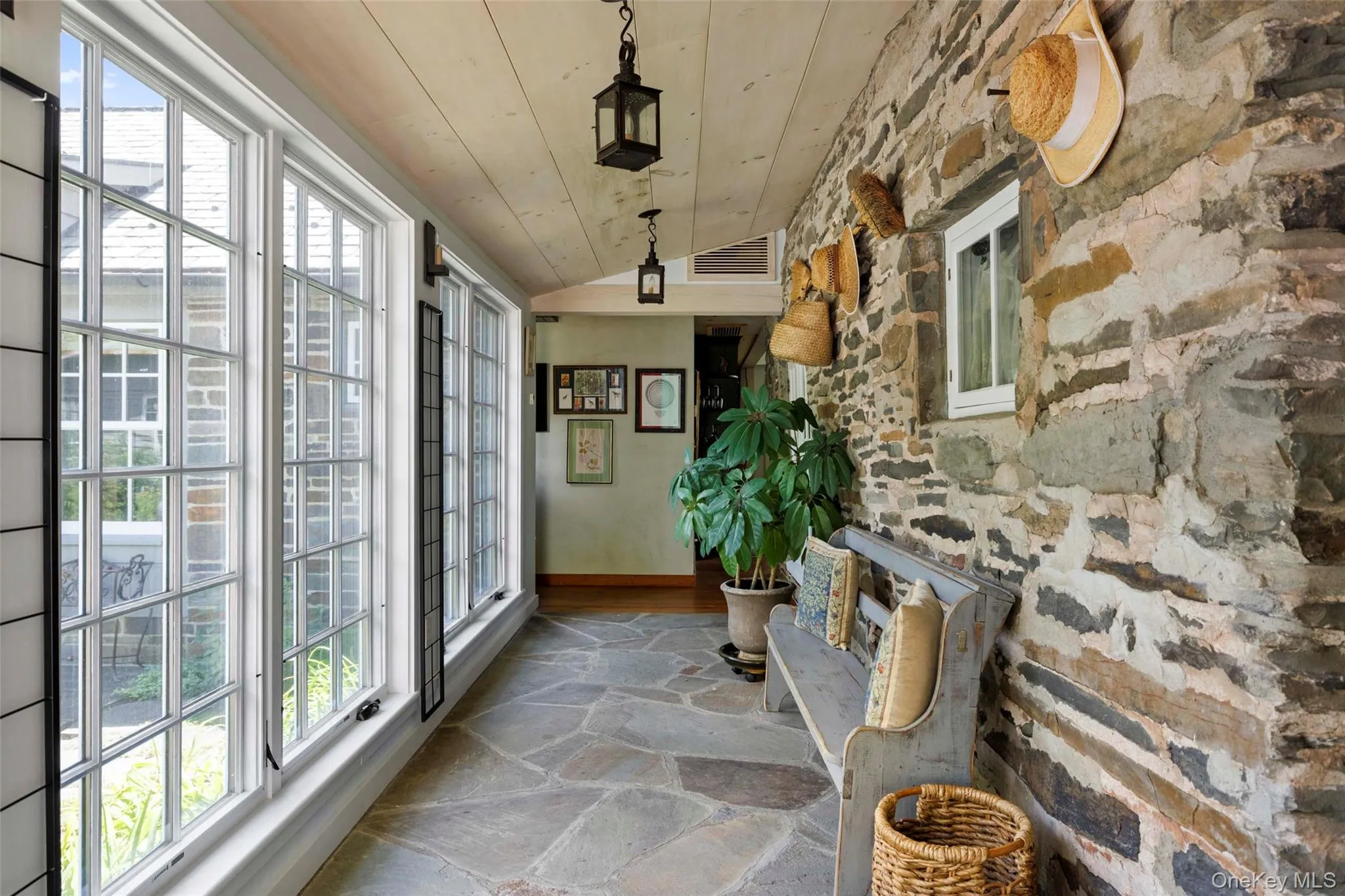 Striking enclosed breezeway with radiant-heated bluestone floors, exposed stone walls, and views across the central courtyard Striking enclosed breezeway with radiant-heated bluestone floors, exposed stone walls, and views across the central courtyard