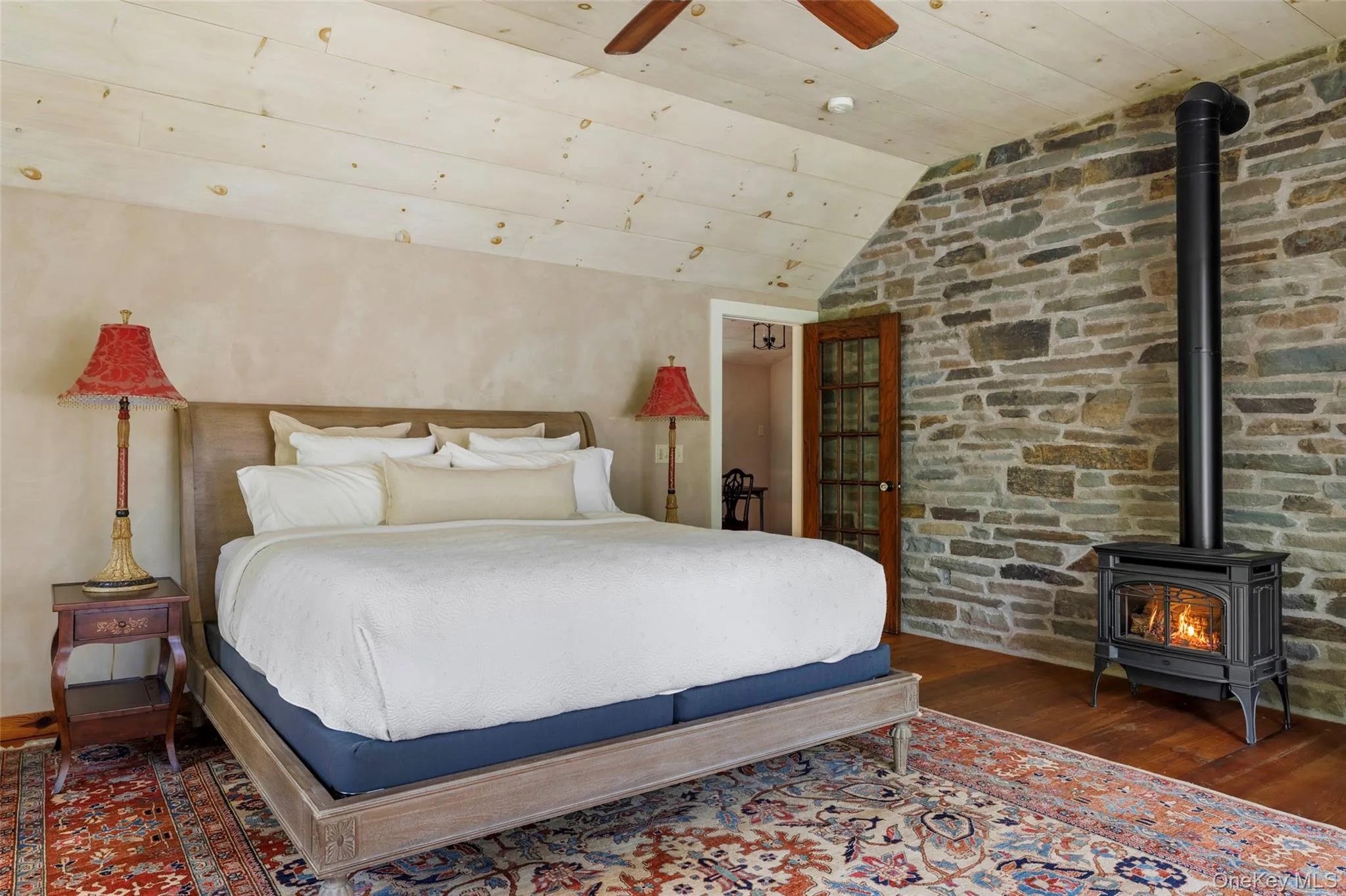 Vaulted ceiling, exposed stone wall, wood stove and adjoining private study Vaulted ceiling, exposed stone wall, wood stove and adjoining private study