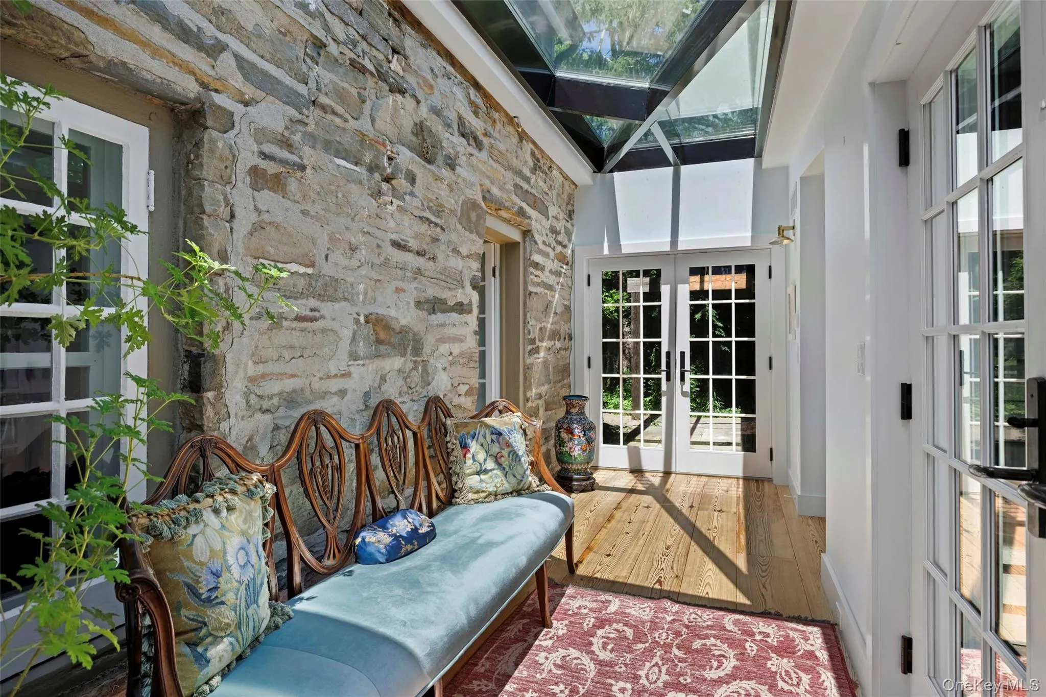 This thoughtfully designed glass-enclosed passage preserves the original stone wall while dramatic skylights flood the space with natural light, creating a seamless connection between the historic farmhouse and the newer west wing This thoughtfully designed glass-enclosed passage preserves the original stone wall while dramatic skylights flood the space with natural light, creating a seamless connection between the historic farmhouse and the newer west wing