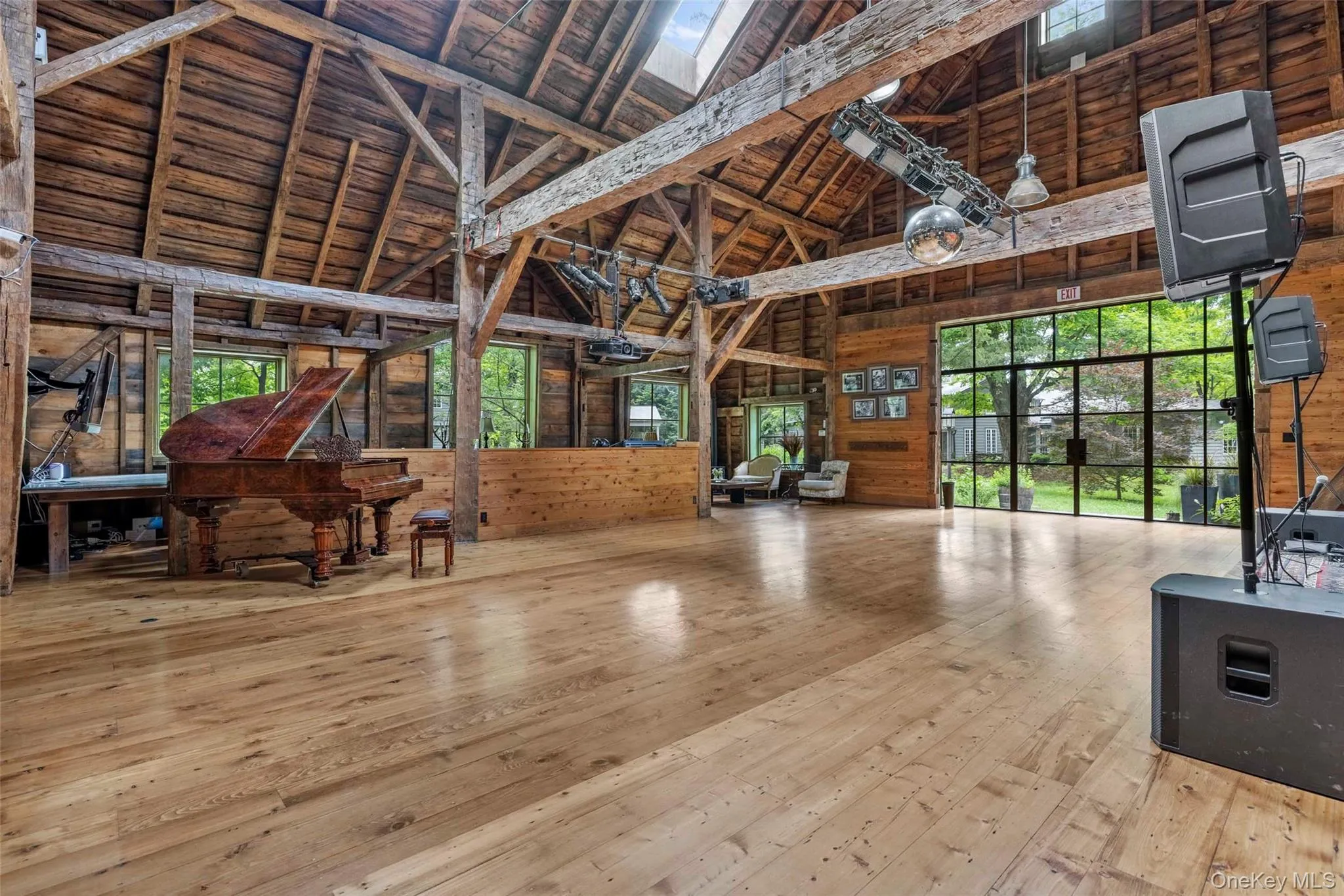 Soaring post-and-beam great hall with expansive glass doors opening to the surrounding gardens Soaring post-and-beam great hall with expansive glass doors opening to the surrounding gardens