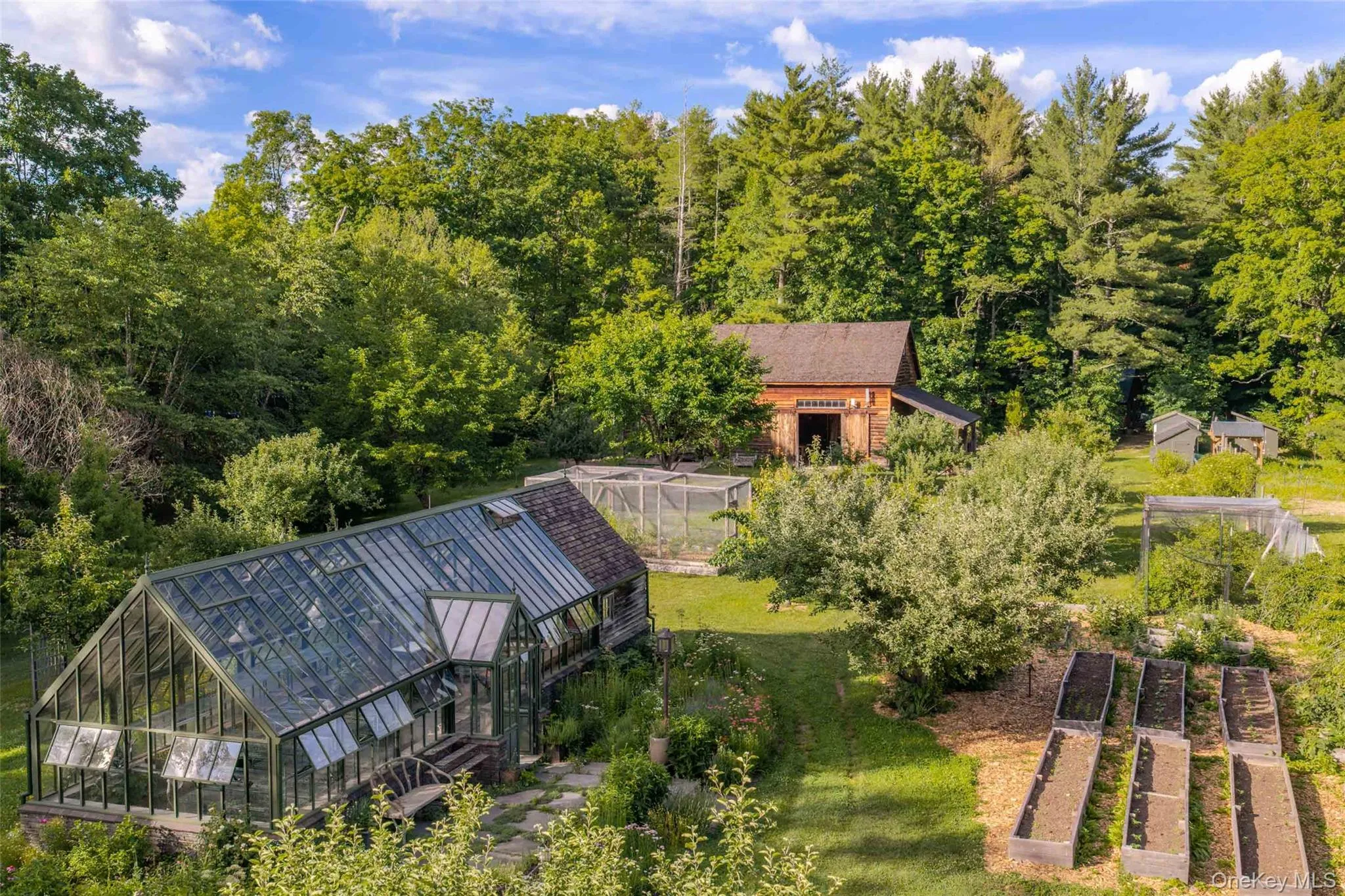 Greenhouse surrounded by medicinal and edible gardens, raised beds, and the historic Cairo Barn beyond Greenhouse surrounded by medicinal and edible gardens, raised beds, and the historic Cairo Barn beyond