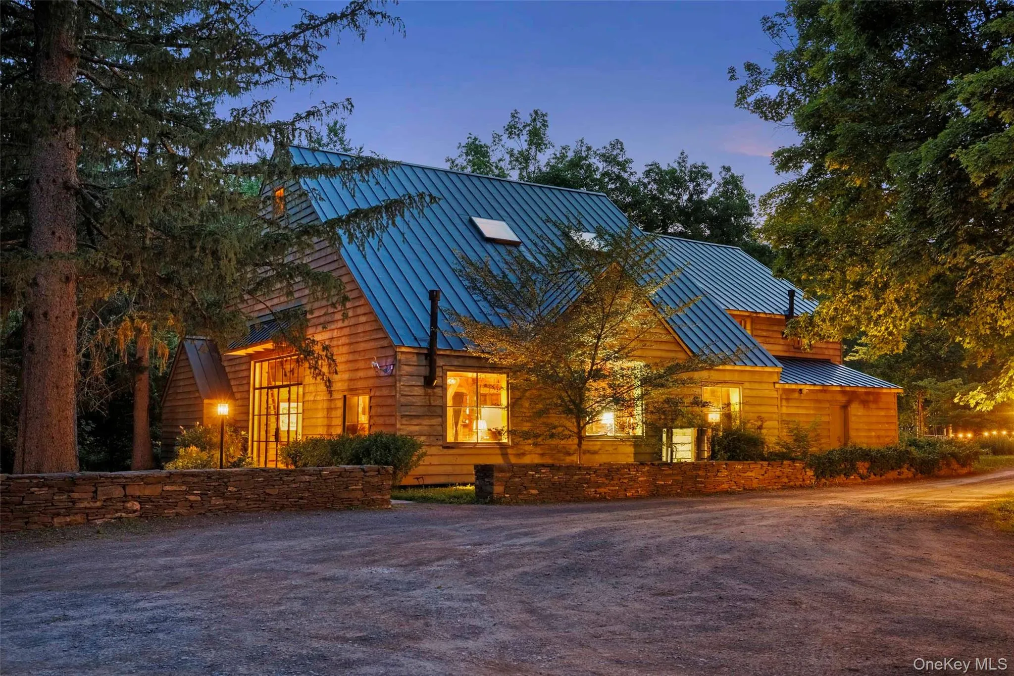 As evening falls, the restored post-and-beam barn takes on an inviting warmth, beautifully illuminated from within As evening falls, the restored post-and-beam barn takes on an inviting warmth, beautifully illuminated from within