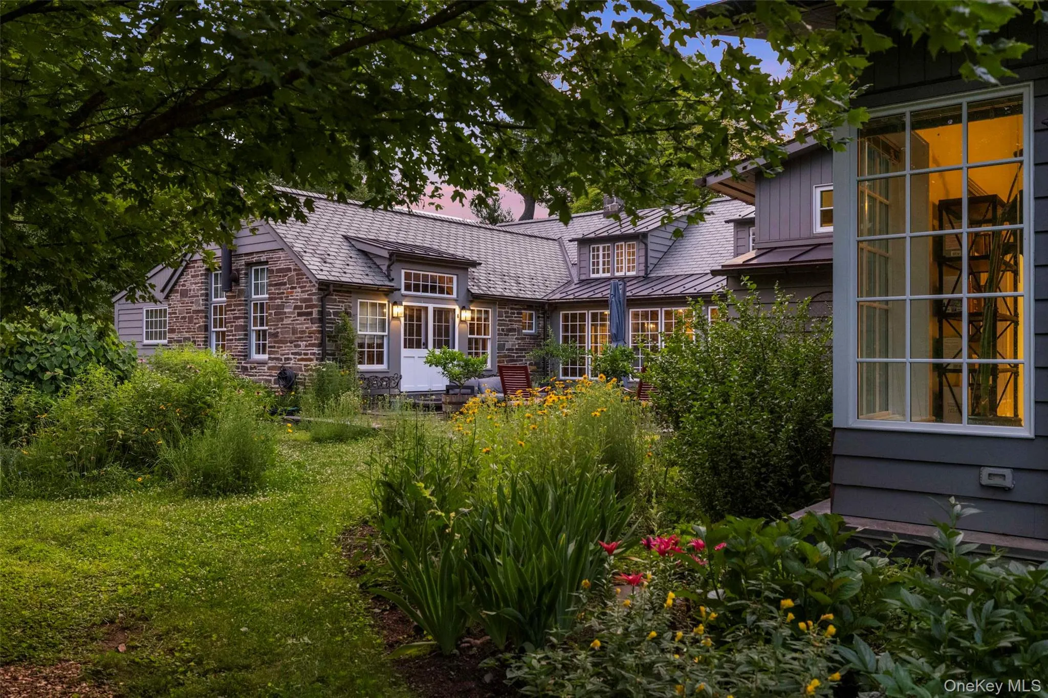 A beautifully landscaped courtyard transforms at dusk, creating an intimate outdoor setting surrounded by the warmth of the historic stone farmhouse and its thoughtfully designed wings A beautifully landscaped courtyard transforms at dusk, creating an intimate outdoor setting surrounded by the warmth of the historic stone farmhouse and its thoughtfully designed wings