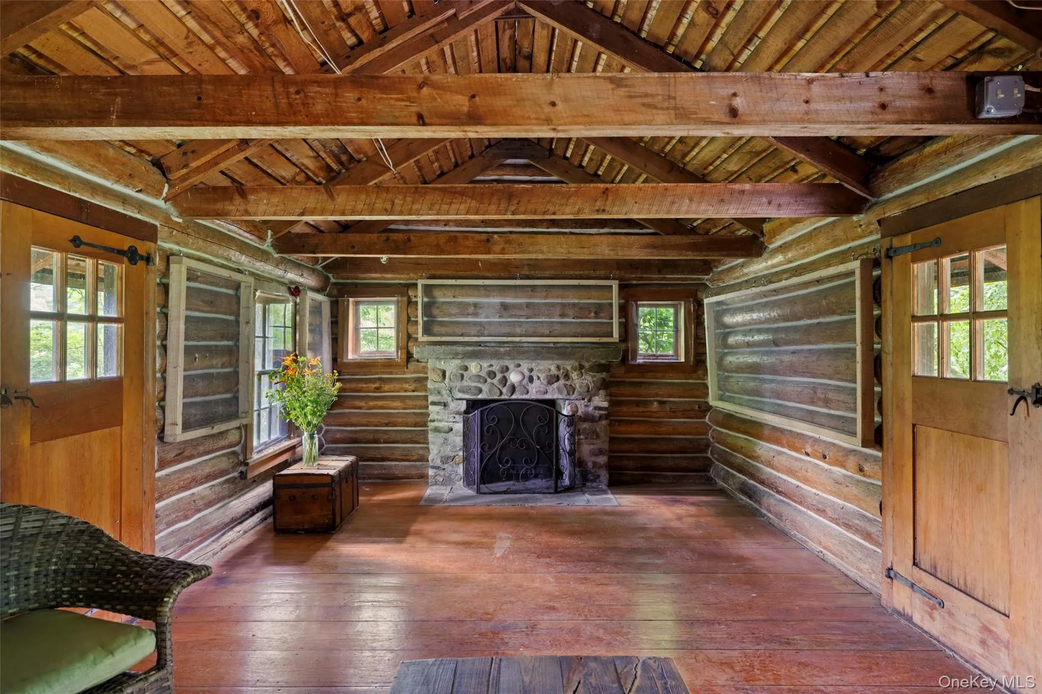 Rustic cabin interior with exposed log walls, hand-hewn beams, and a stone, wood-burning fireplace Rustic cabin interior with exposed log walls, hand-hewn beams, and a stone, wood-burning fireplace