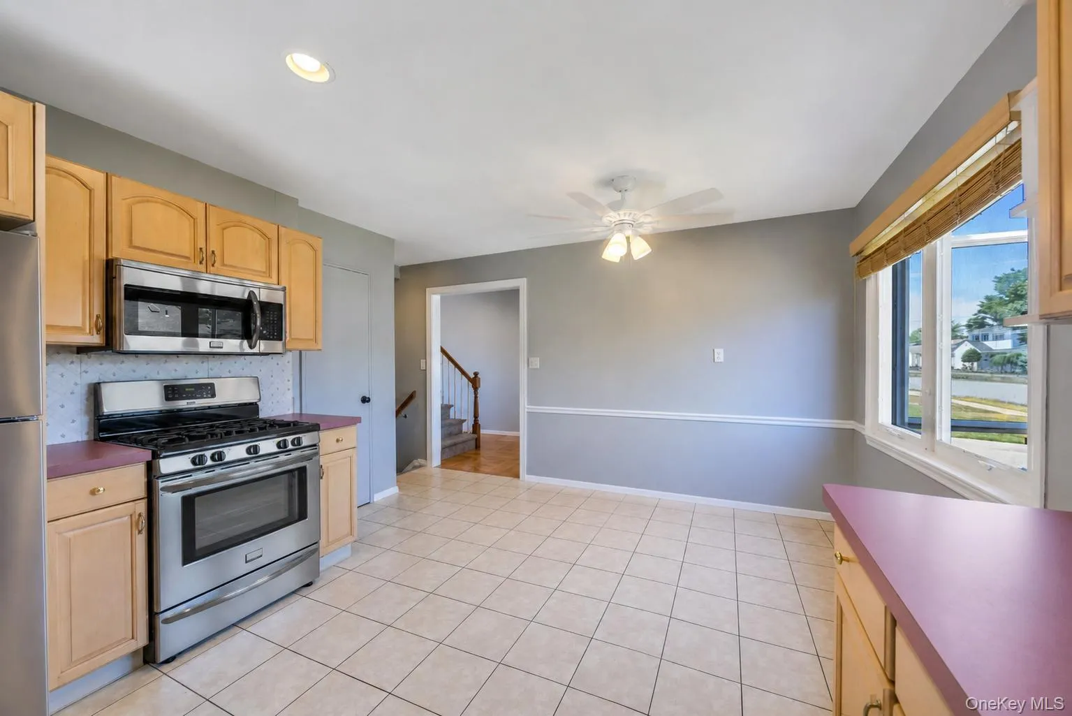 Eat-in kitchen featuring light wood-finish cabinetry, stainless steel appliances, and tile flooring Eat-in kitchen featuring light wood-finish cabinetry, stainless steel appliances, and tile flooring