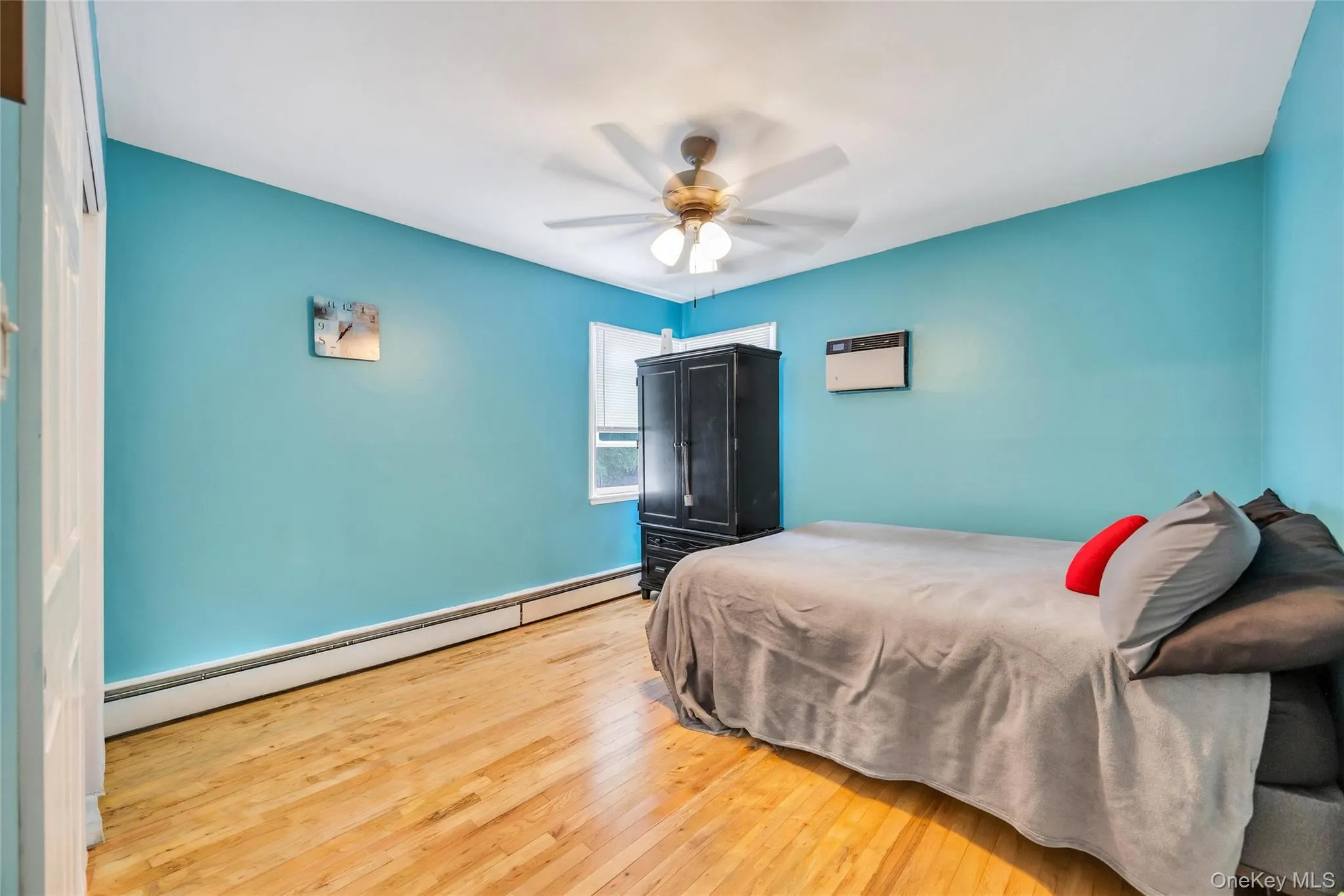 Bright interior room featuring wood-finish flooring, a ceiling fan with integrated lighting, and a window for natural light Bright interior room featuring wood-finish flooring, a ceiling fan with integrated lighting, and a window for natural light