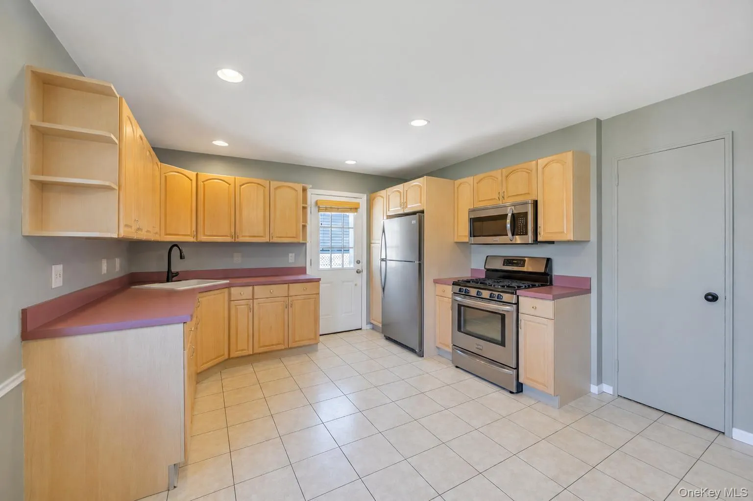 Kitchen featuring light wood cabinetry and light-colored tile flooring Kitchen featuring light wood cabinetry and light-colored tile flooring
