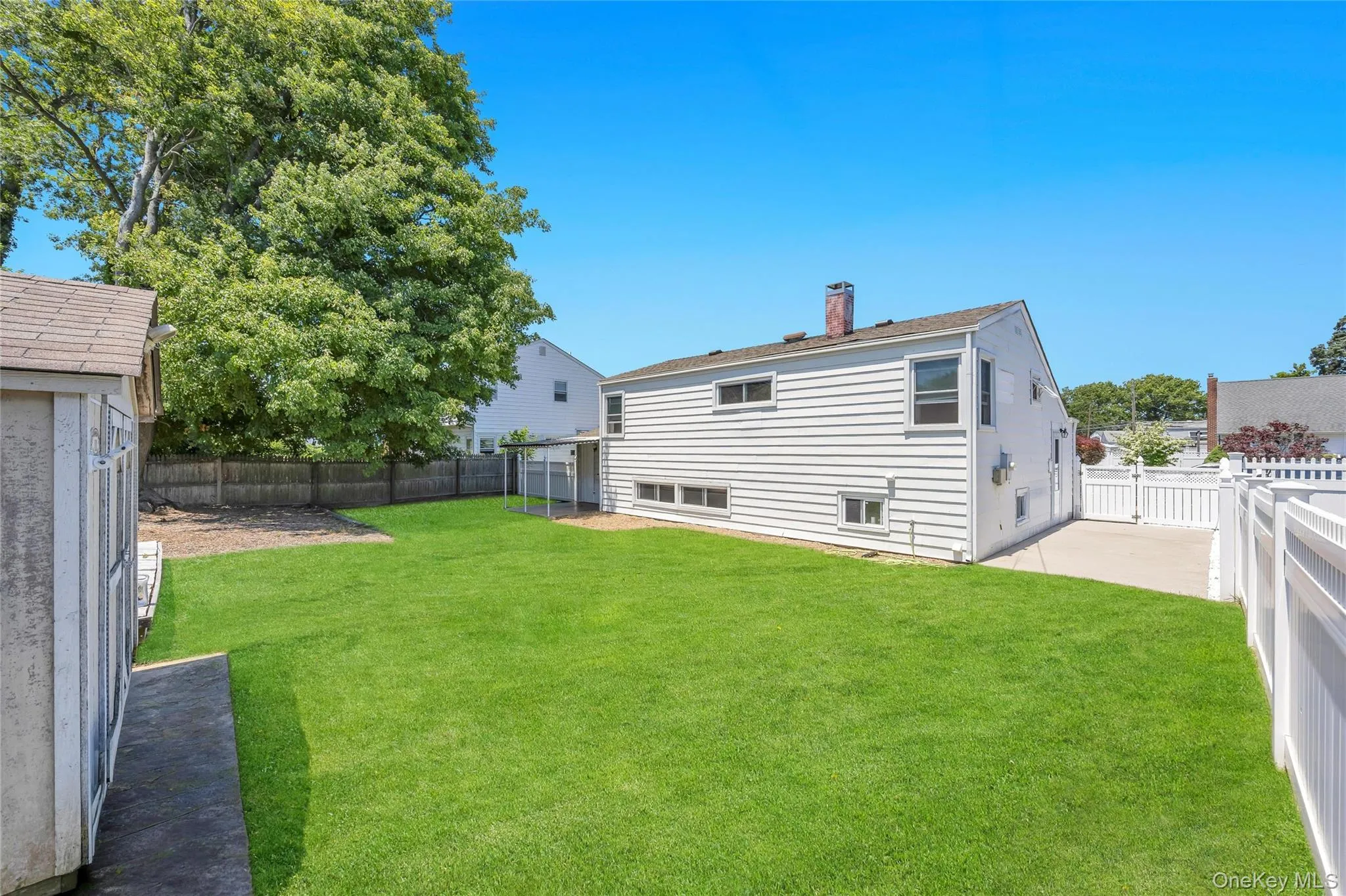Expansive rear yard featuring a manicured lawn, established mature tree, and a storage shed Expansive rear yard featuring a manicured lawn, established mature tree, and a storage shed