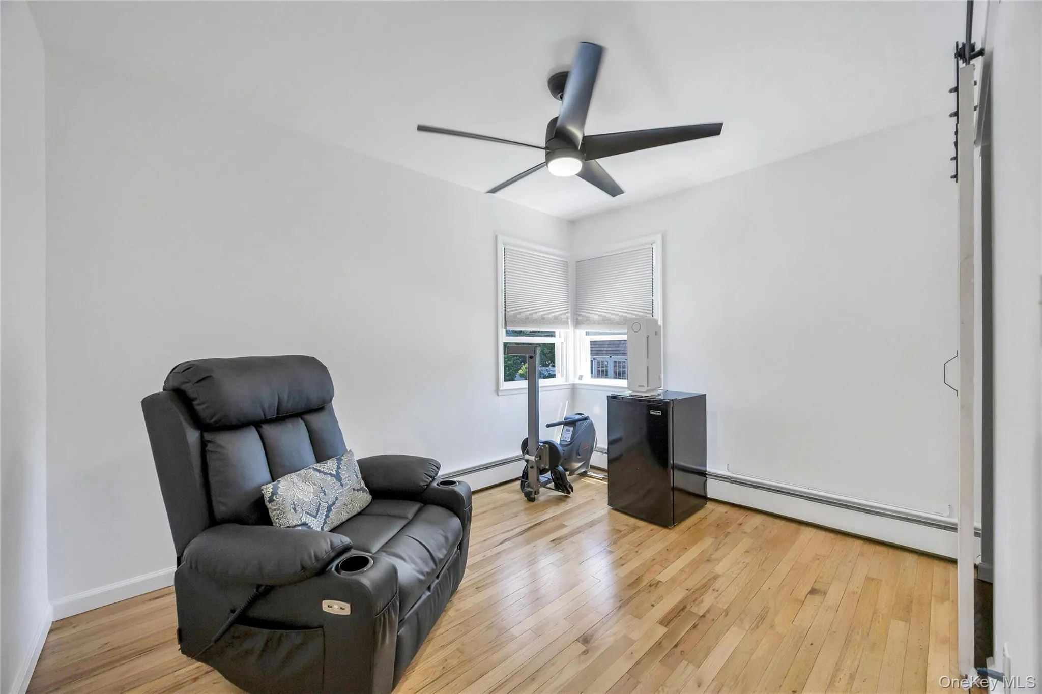 Bright room featuring wood-finish flooring and a contemporary ceiling fan with integrated lighting Bright room featuring wood-finish flooring and a contemporary ceiling fan with integrated lighting