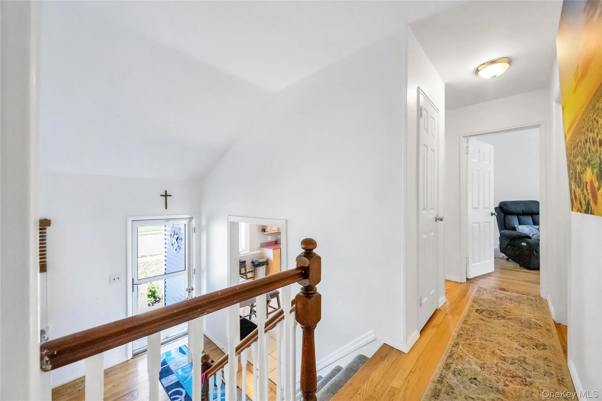 Upper-level hallway featuring wood-finish flooring, white paneled doors, and a flush-mount ceiling light Upper-level hallway featuring wood-finish flooring, white paneled doors, and a flush-mount ceiling light