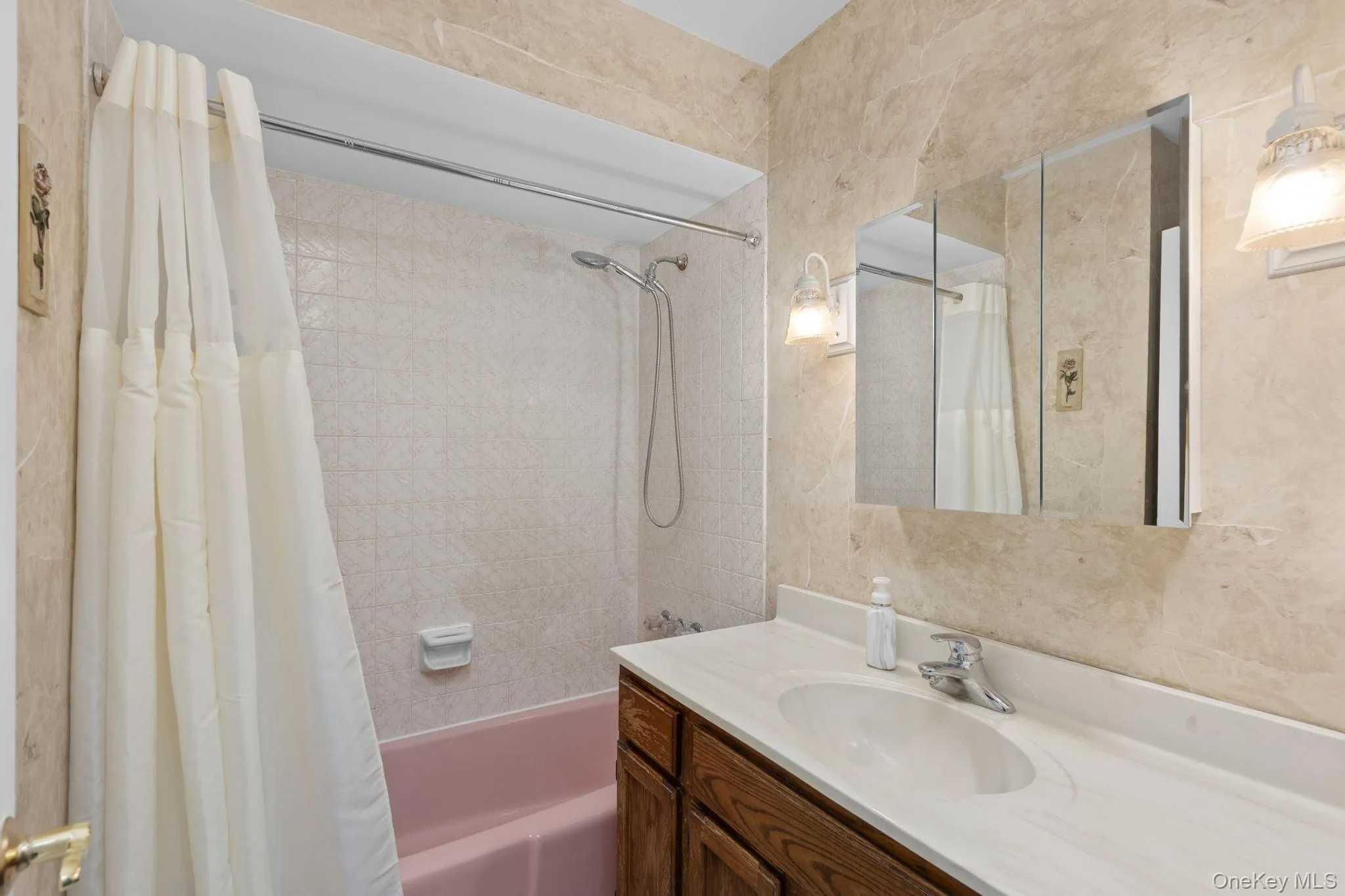 Bathroom with pink soaking tub, tri-view medicine cabinet and wood vanity. Bathroom with pink soaking tub, tri-view medicine cabinet and wood vanity.