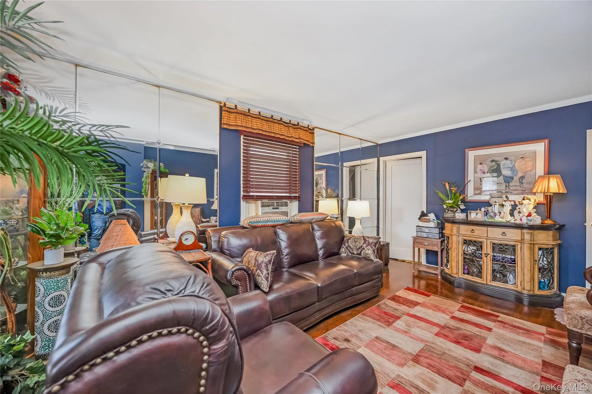Living area featuring rich blue walls, hardwood flooring, and a mirrored wall accent Living area featuring rich blue walls, hardwood flooring, and a mirrored wall accent