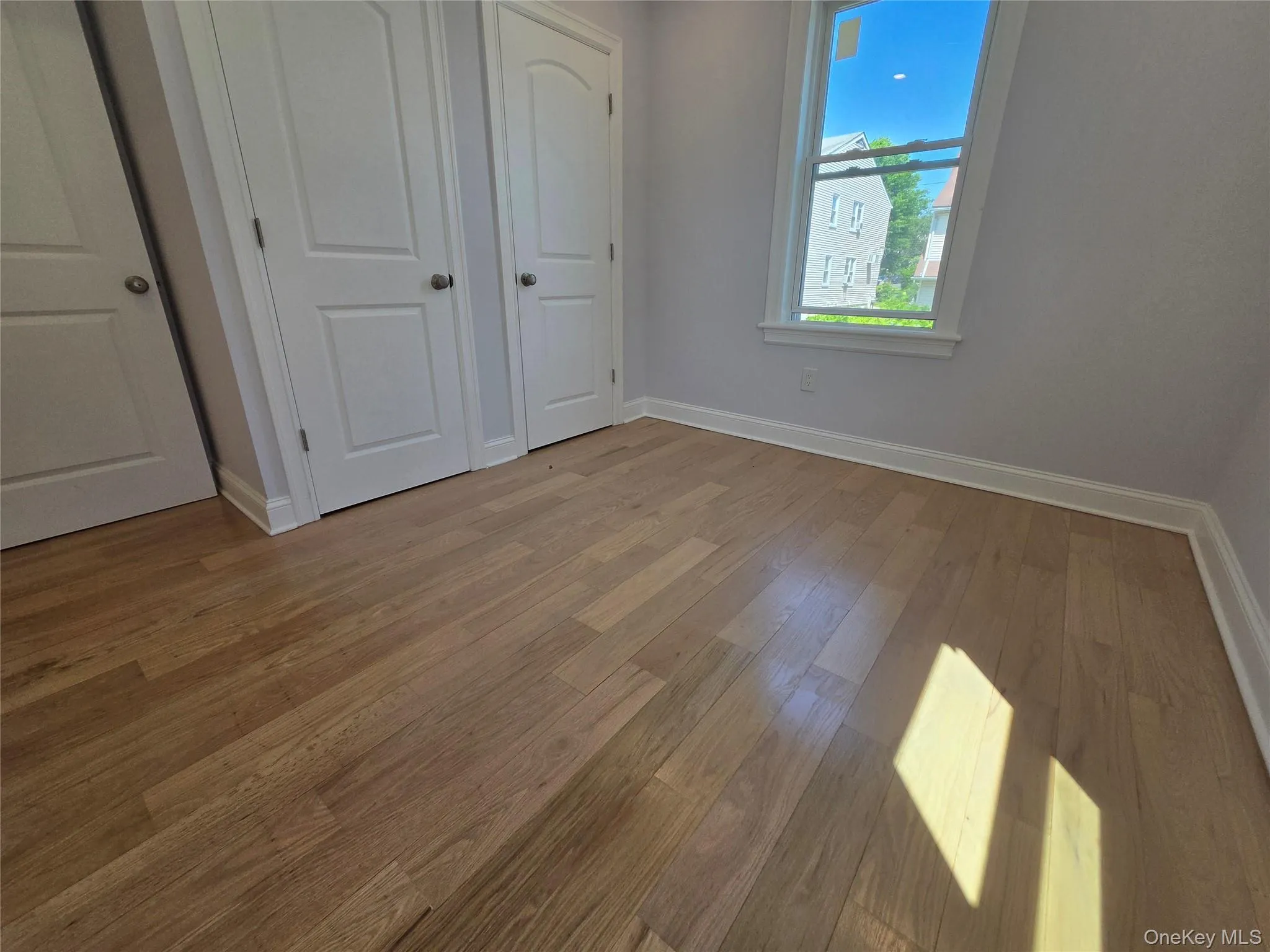 Hardwood flooring throughout featuring baseboard molding and a window with white trim Hardwood flooring throughout featuring baseboard molding and a window with white trim