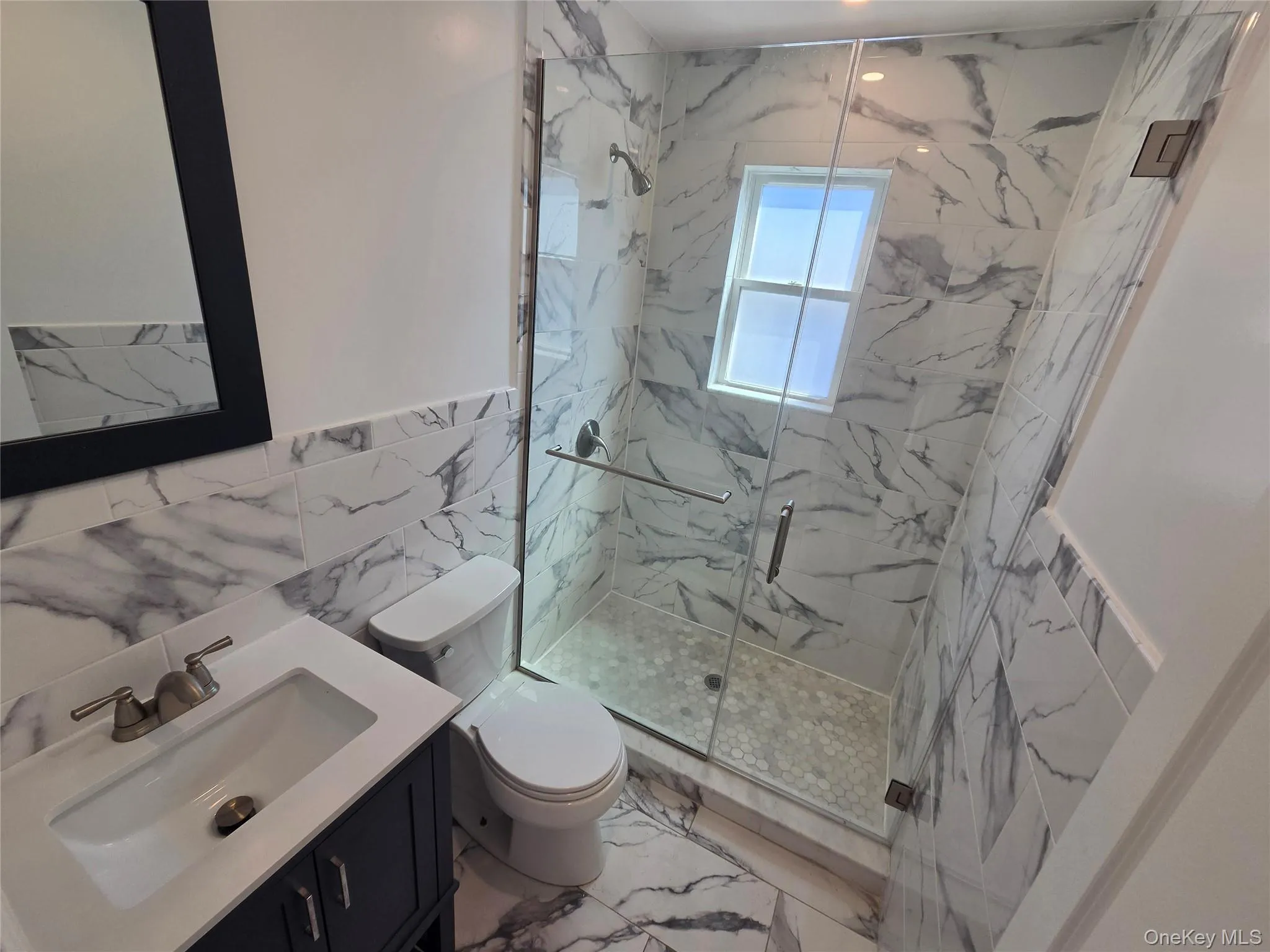 Modern bathroom featuring a glass-enclosed shower with honeycomb-patterned floor tiles Modern bathroom featuring a glass-enclosed shower with honeycomb-patterned floor tiles