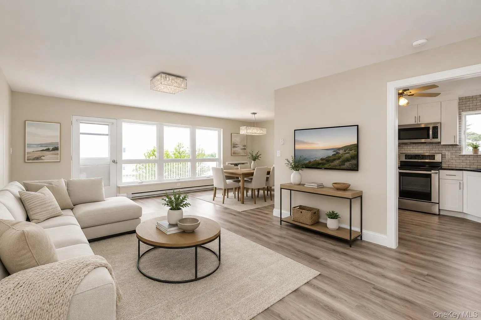 Spacious living area with wood-finish flooring, ample natural light from extensive window systems, and a contemporary crystal chandelier Spacious living area with wood-finish flooring, ample natural light from extensive window systems, and a contemporary crystal chandelier