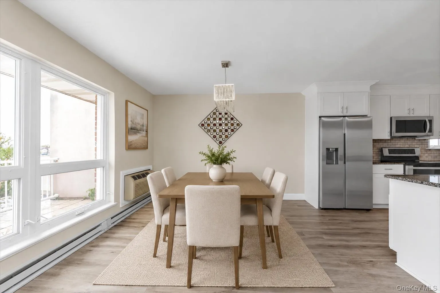 Open-concept dining area featuring wood-finish flooring, white trim, and a contemporary chandelier Open-concept dining area featuring wood-finish flooring, white trim, and a contemporary chandelier