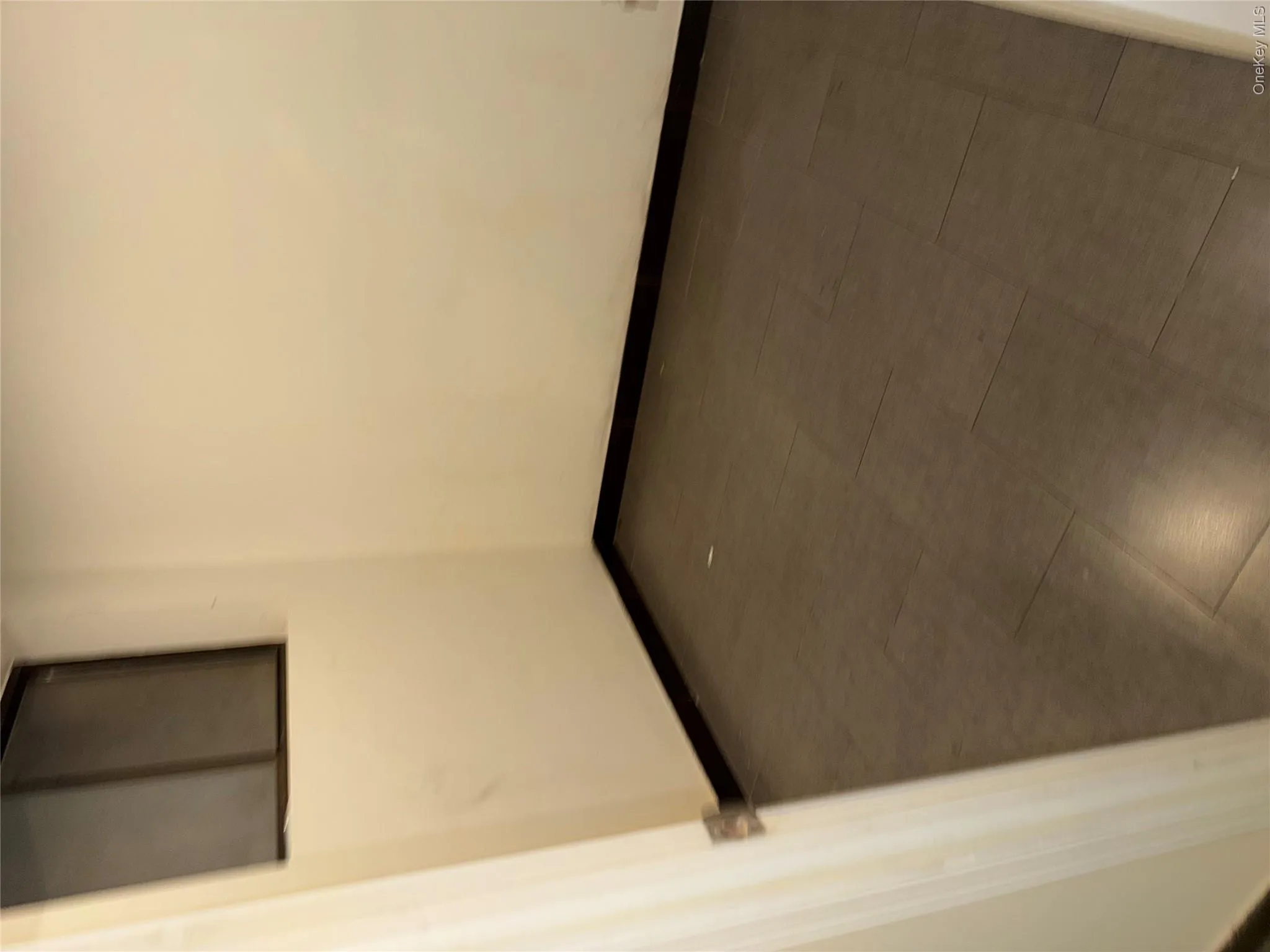 Compact room featuring light-colored walls, dark baseboards, and a window with a dark frame Compact room featuring light-colored walls, dark baseboards, and a window with a dark frame