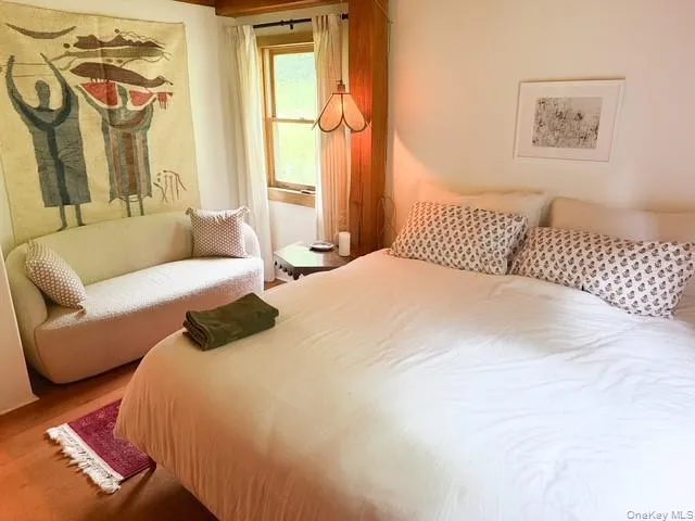 Bedroom featuring wood-finish flooring, a wood-framed window, and a built-in wood column Bedroom featuring wood-finish flooring, a wood-framed window, and a built-in wood column