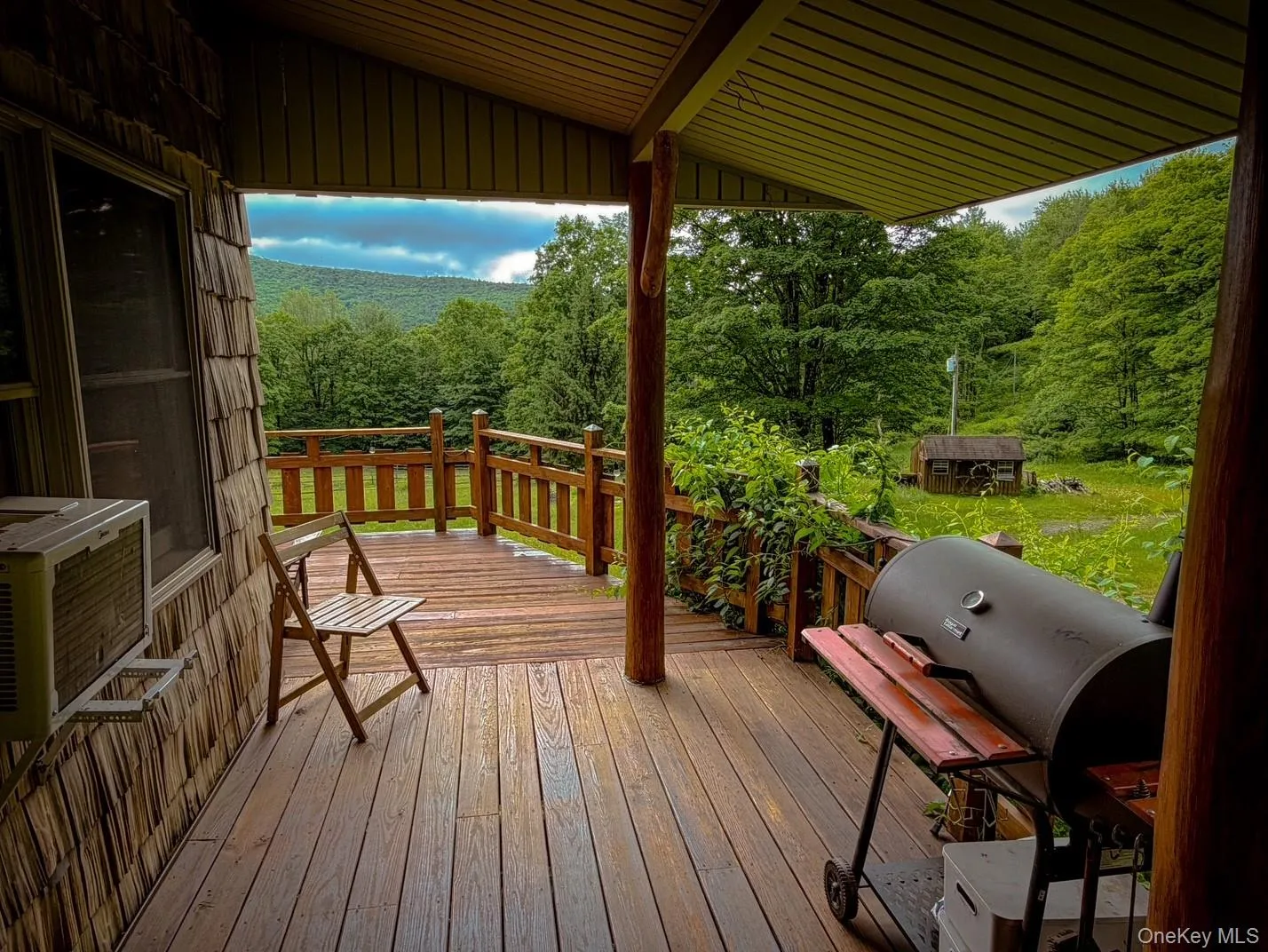 Covered wood-finish deck with wood railing, natural wood siding, and mountain scenery Covered wood-finish deck with wood railing, natural wood siding, and mountain scenery