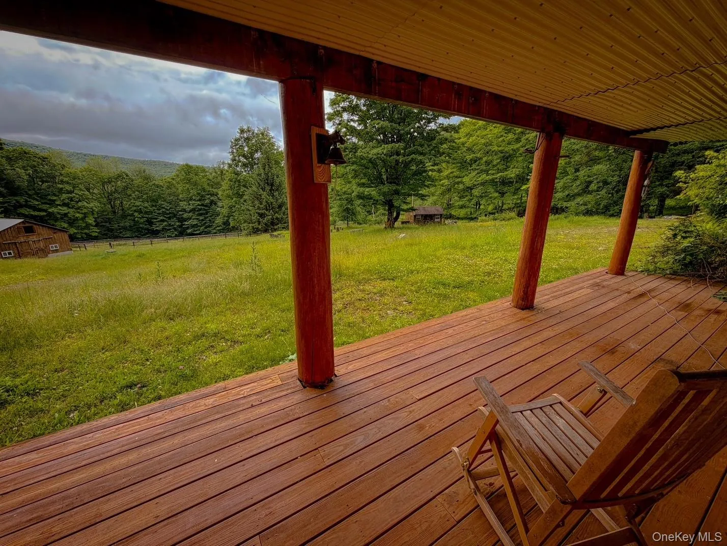 Expansive wood-finish deck with robust support beams and a corrugated metal ceiling Expansive wood-finish deck with robust support beams and a corrugated metal ceiling