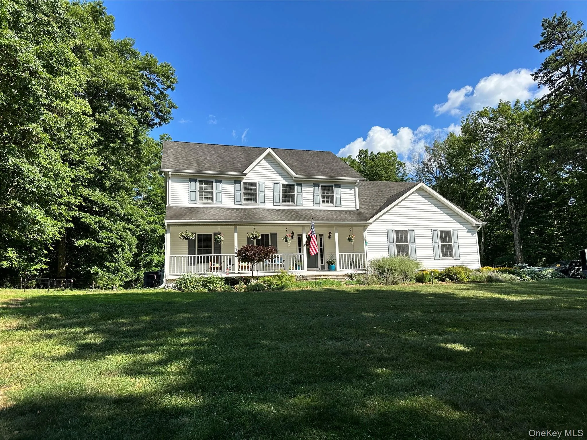 Two-story residence featuring white siding, a covered front porch with white railings, and a multi-level roofline Two-story residence featuring white siding, a covered front porch with white railings, and a multi-level roofline