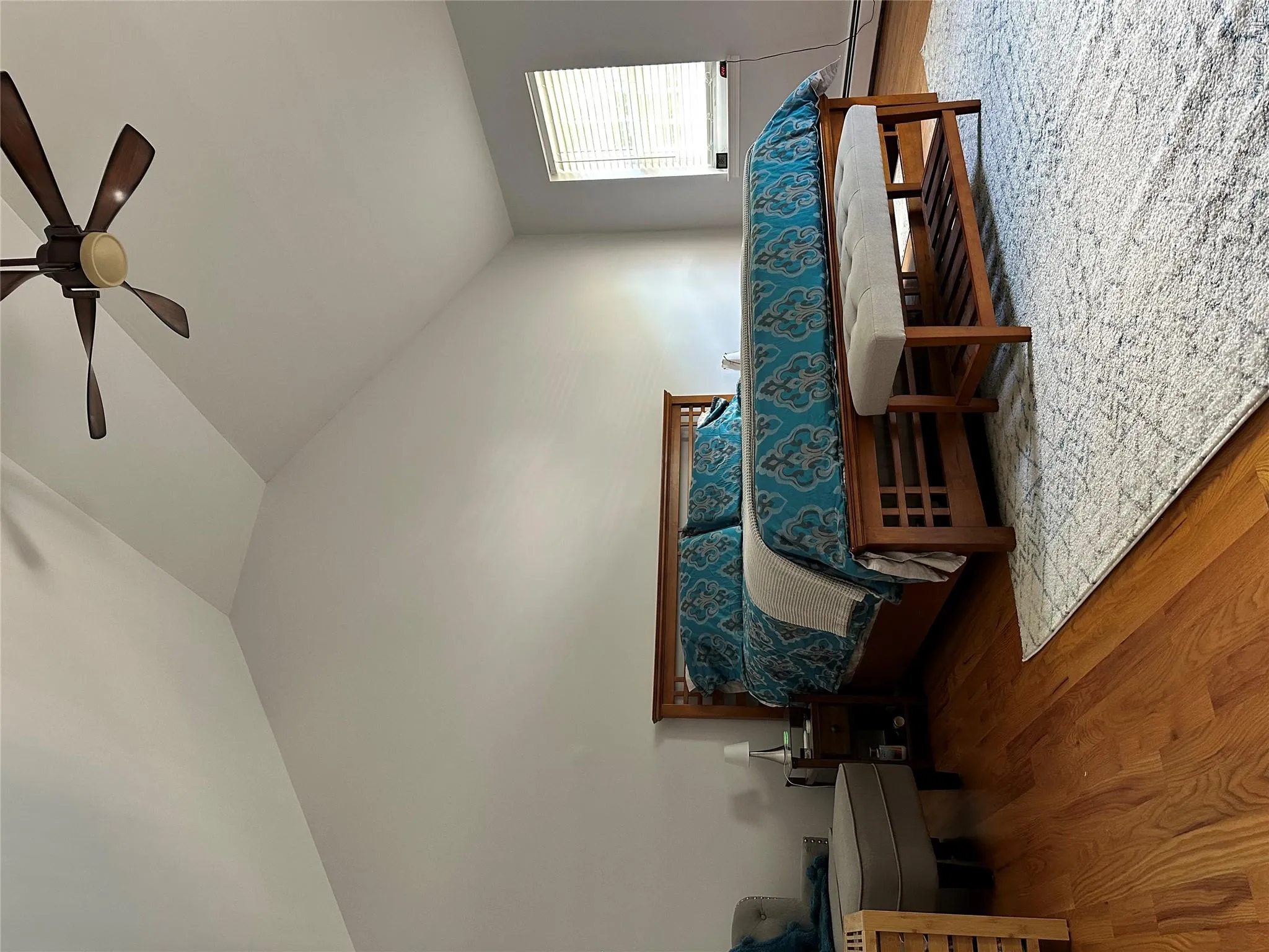 Vaulted ceilings highlight this room featuring wood-finish flooring, a ceiling fan, and a window with horizontal blinds Vaulted ceilings highlight this room featuring wood-finish flooring, a ceiling fan, and a window with horizontal blinds